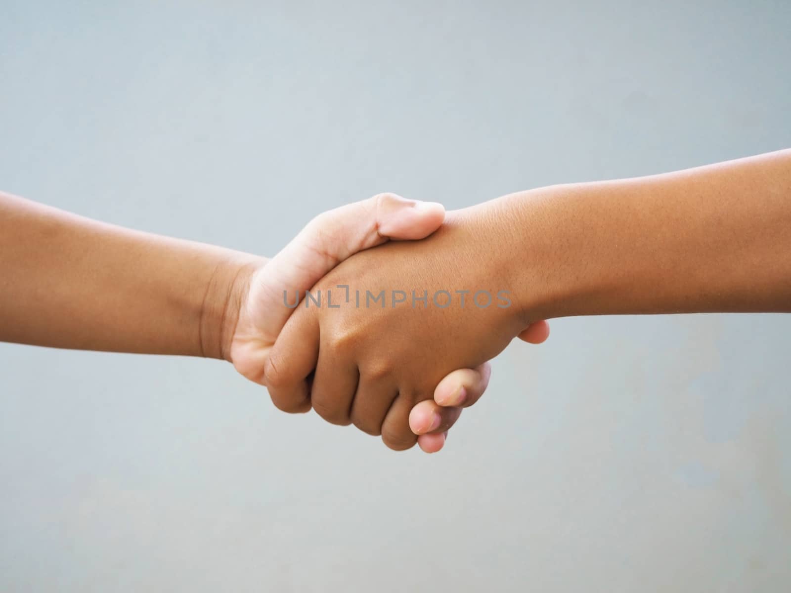 Two male hands shaking isolated on blue studio background. Socia by Unimages2527