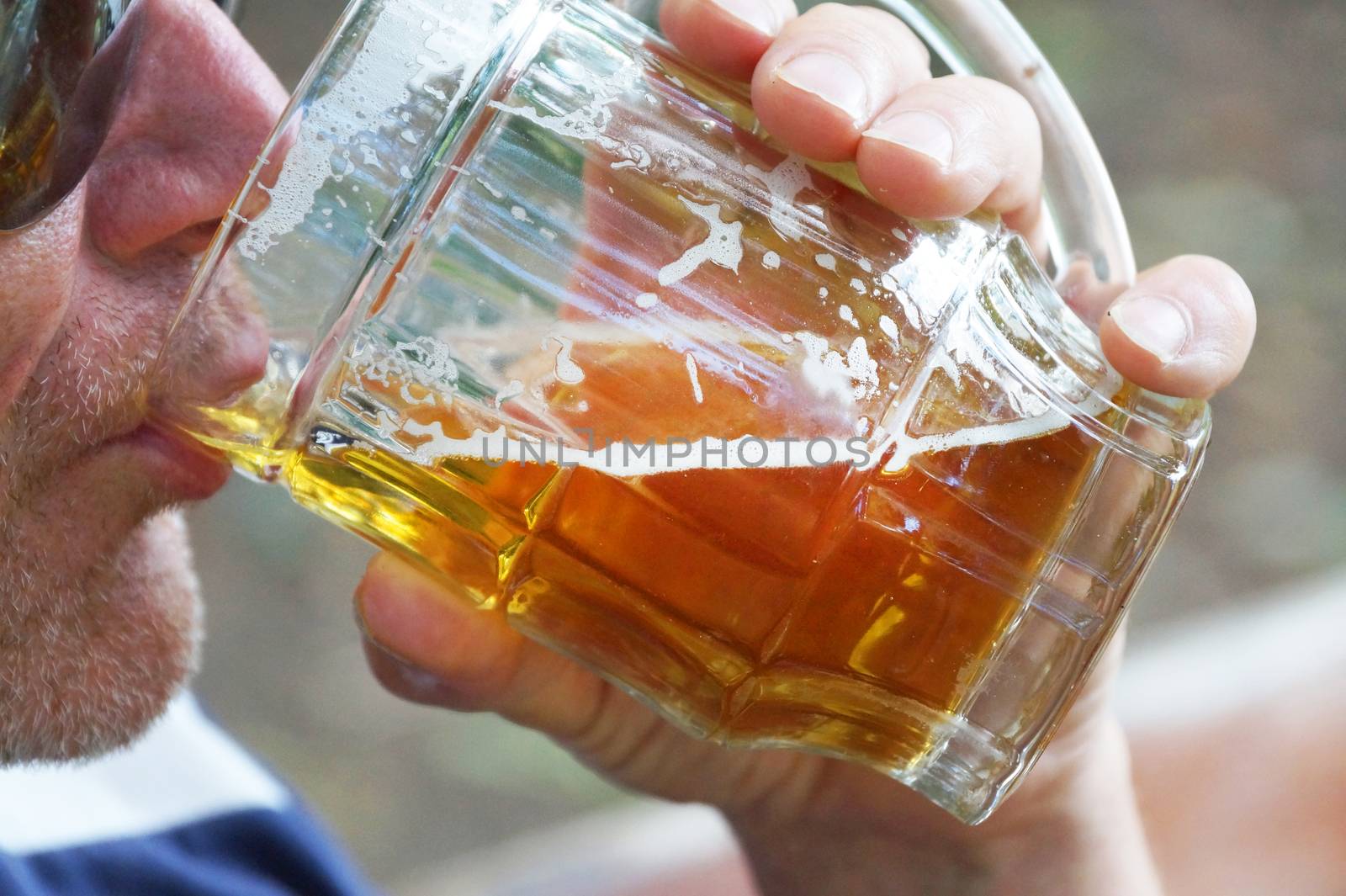 man drinks beer from a large glass mug in nature by Annado