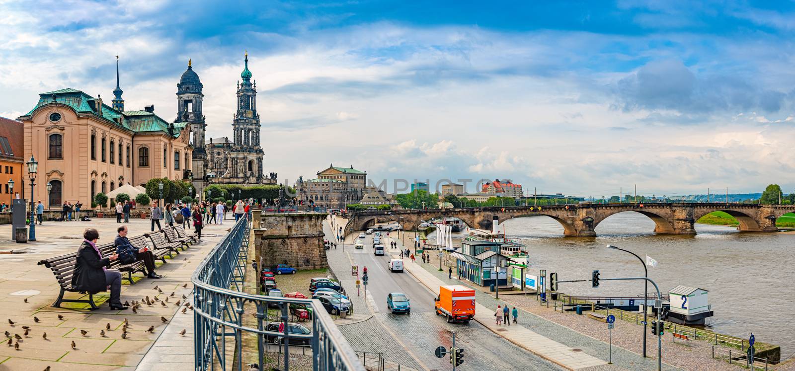 DRESDEN, GERMANY - SEPTEMBER 22, 2014: Katholische Hofkirche on the left and Semperoper on the right. People at river Elbe with bridge in background. Travel and architecture in Europe