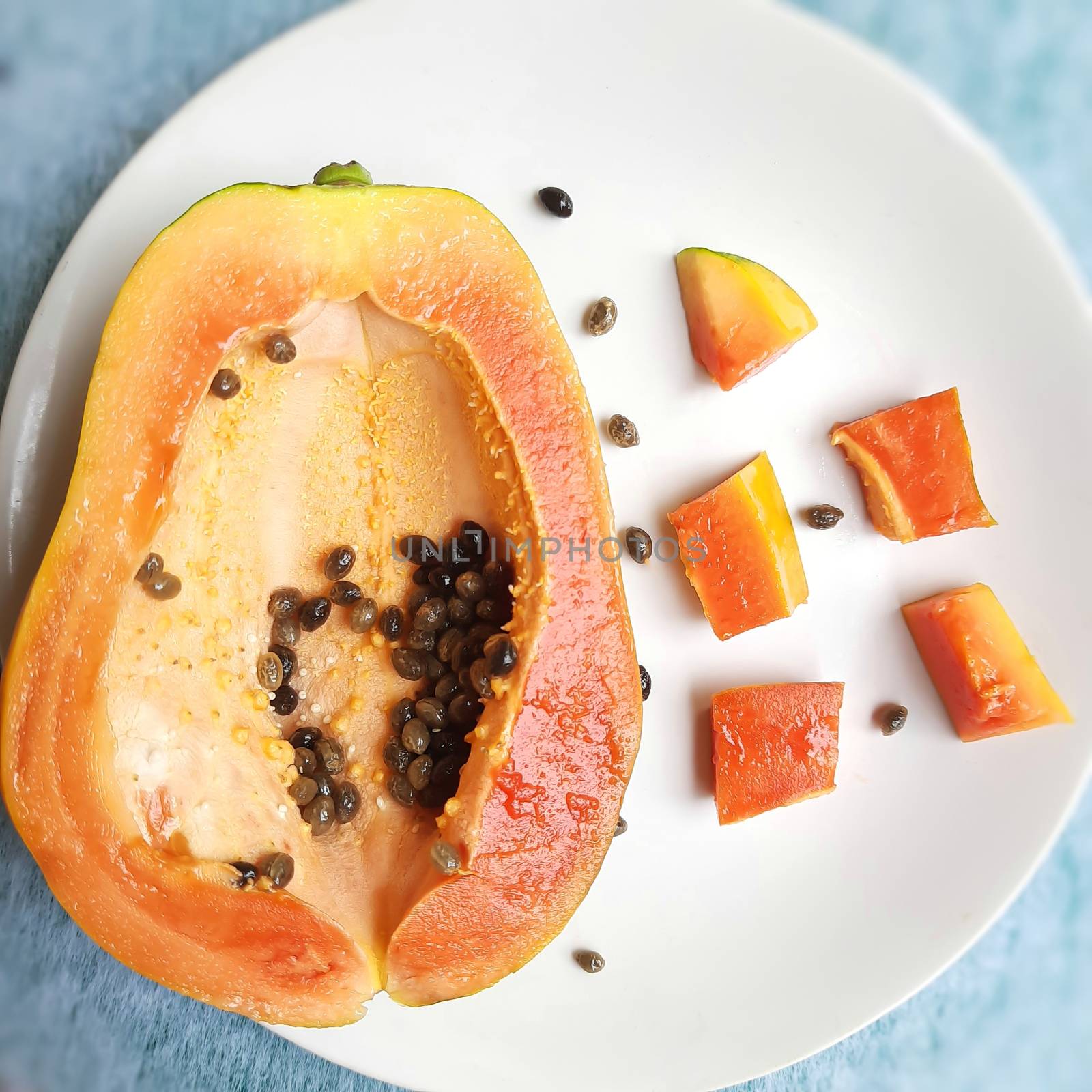 Orange color fresh papaya cut into half and cur pieces kept in white background and rich in fibre Vitamin C and antioxidants Boosts your immunity Good for diabetics and eyes