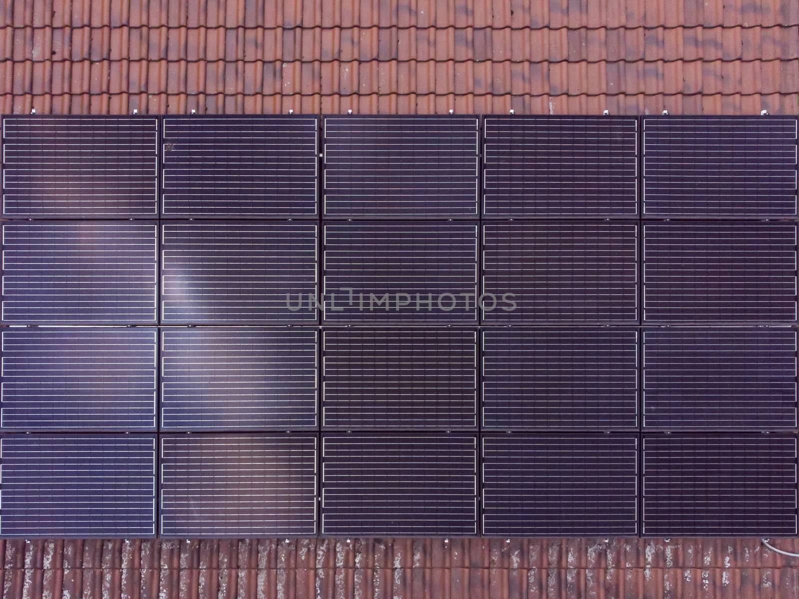 Black solar panels in rectangular shape installed on a tiled roof. Clean energy.