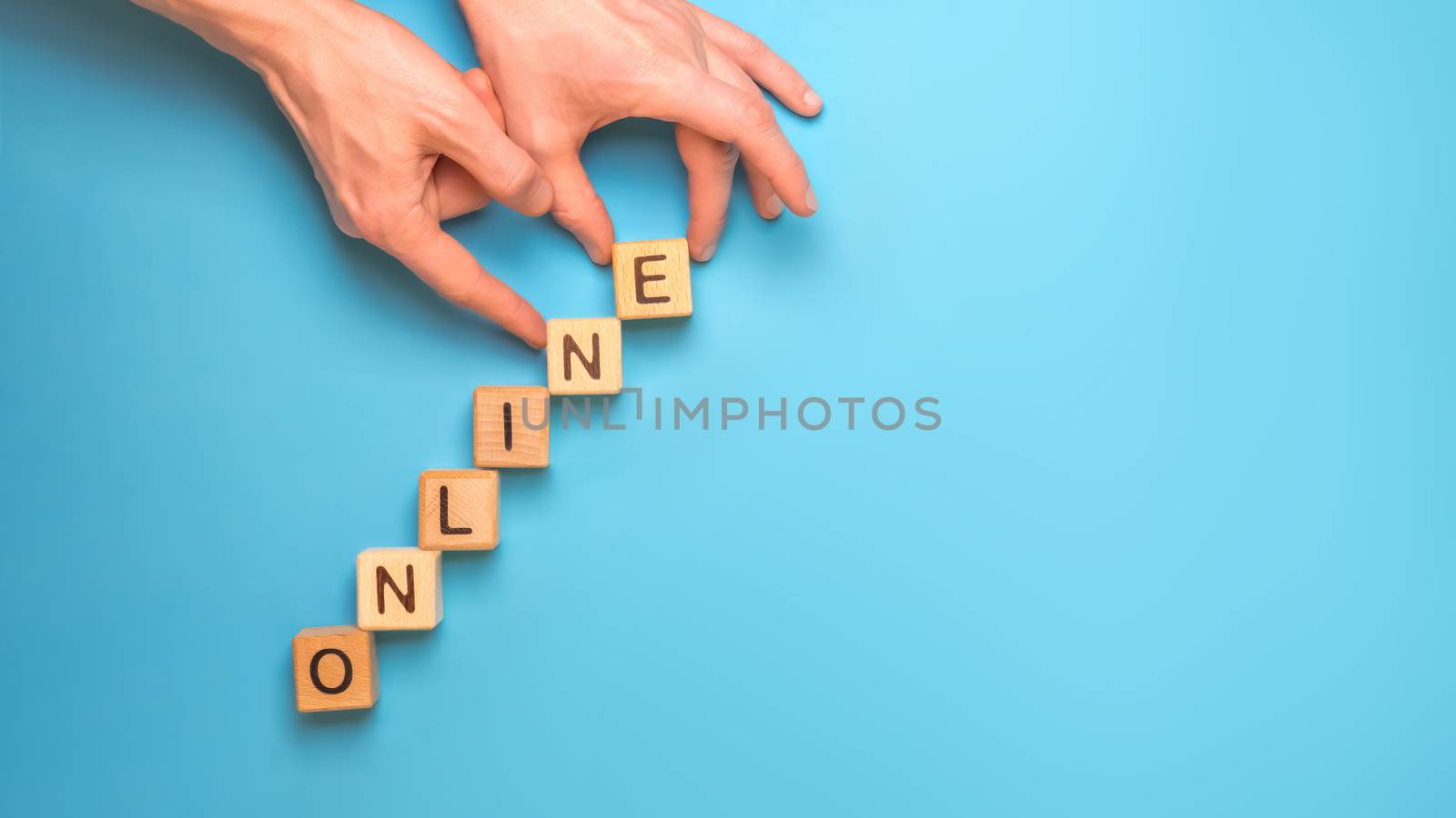 Hands make of word wooden toy cubes online. Word Online made with wooden letterpress cubes on blue background. Stairs growth from wood cubes. Homeschool, modern education. Copy space. Banner online