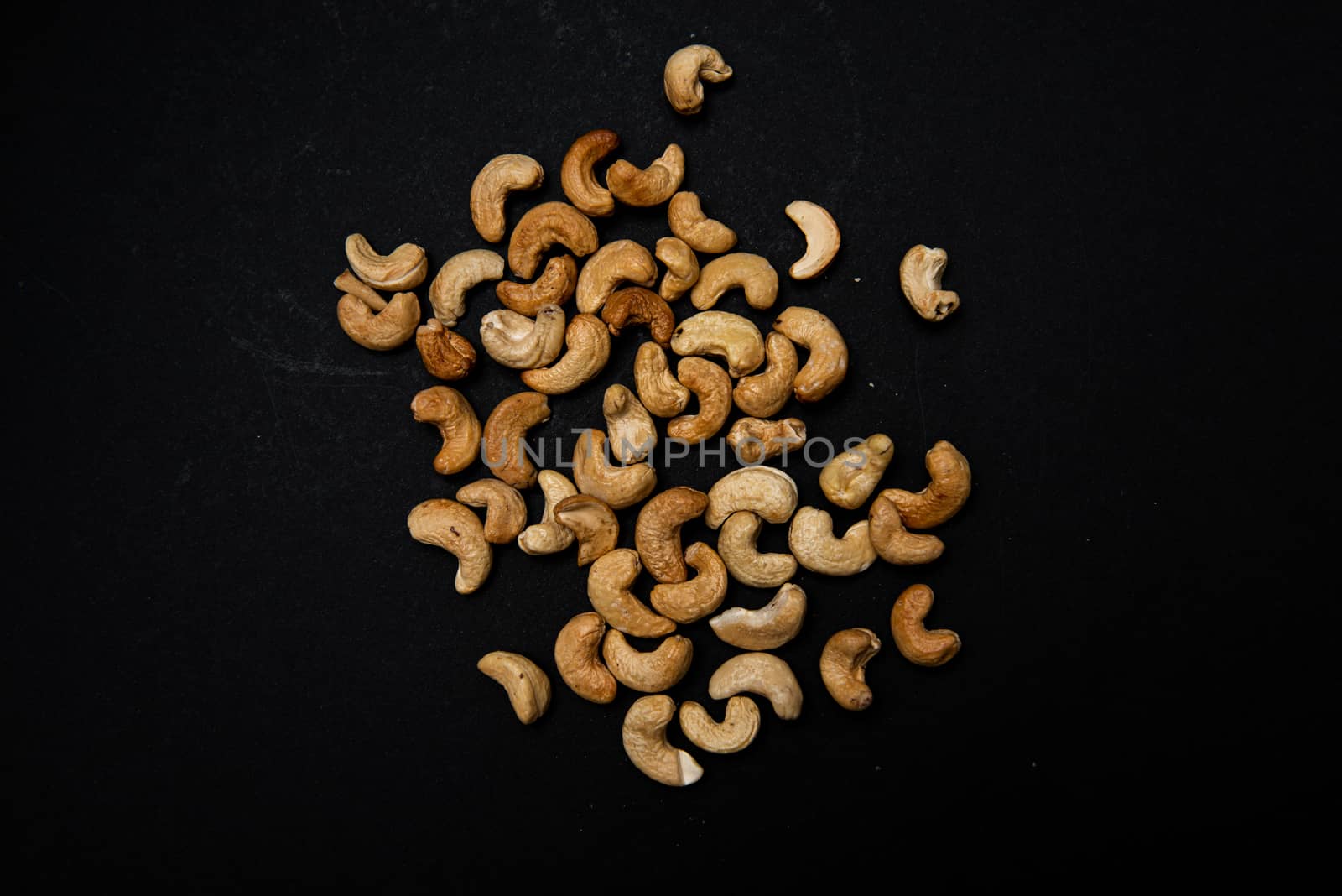 lots of fried cashews nuts scattered on black background with copy space by marynkin