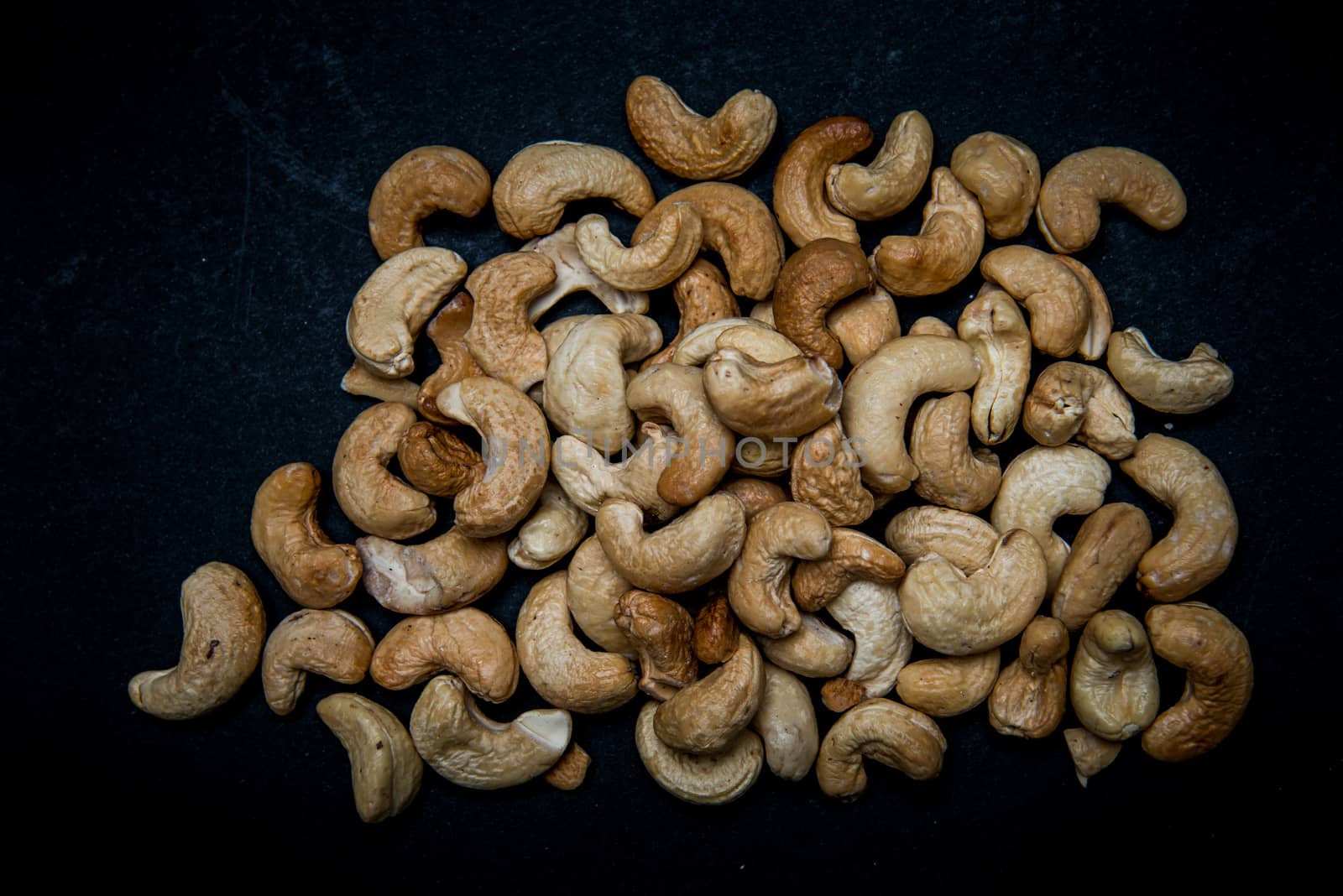 lots of fried cashews nuts scattered on grey background with copy space by marynkin