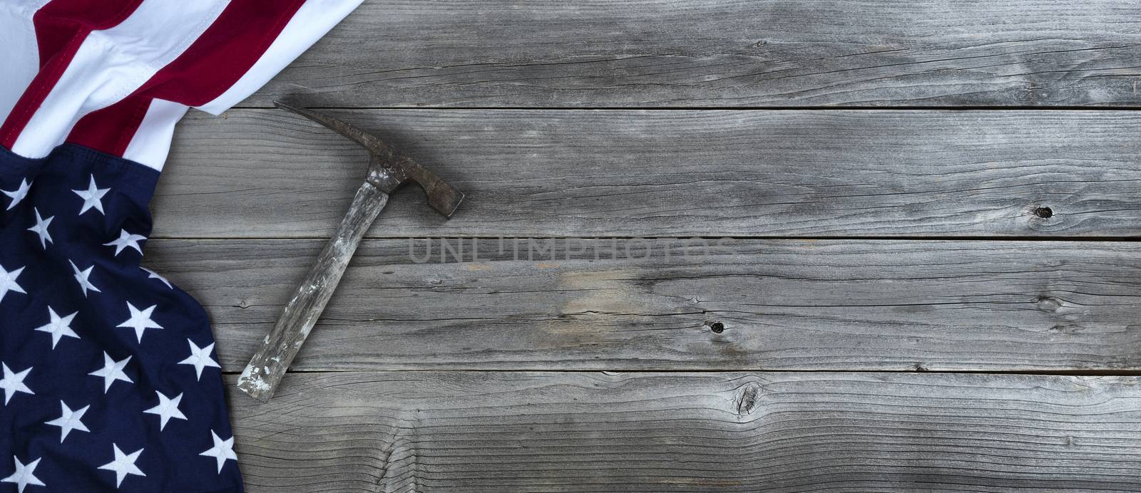 Waving US flag with vintage construction hammer on weathered woo by tab1962