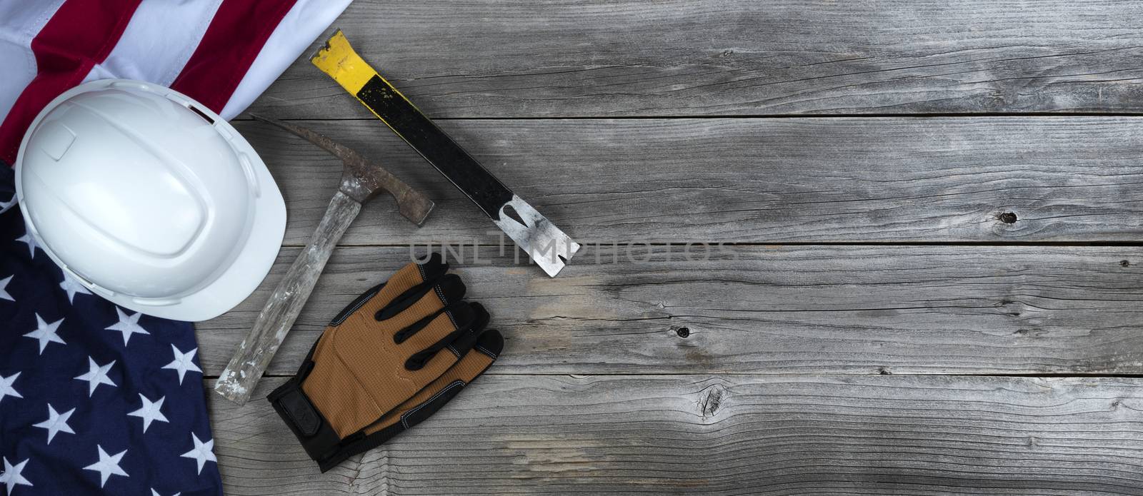 Construction hammer with waving US Flag on rustic wooden background with copy space for Labor Day concept 