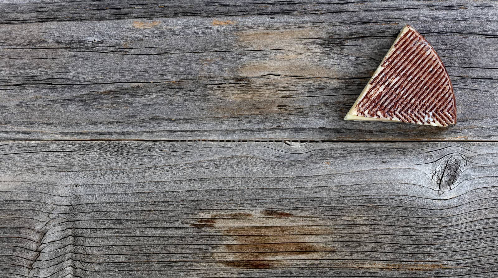 Fresh cheese wedge on rustic wood with copy space available 