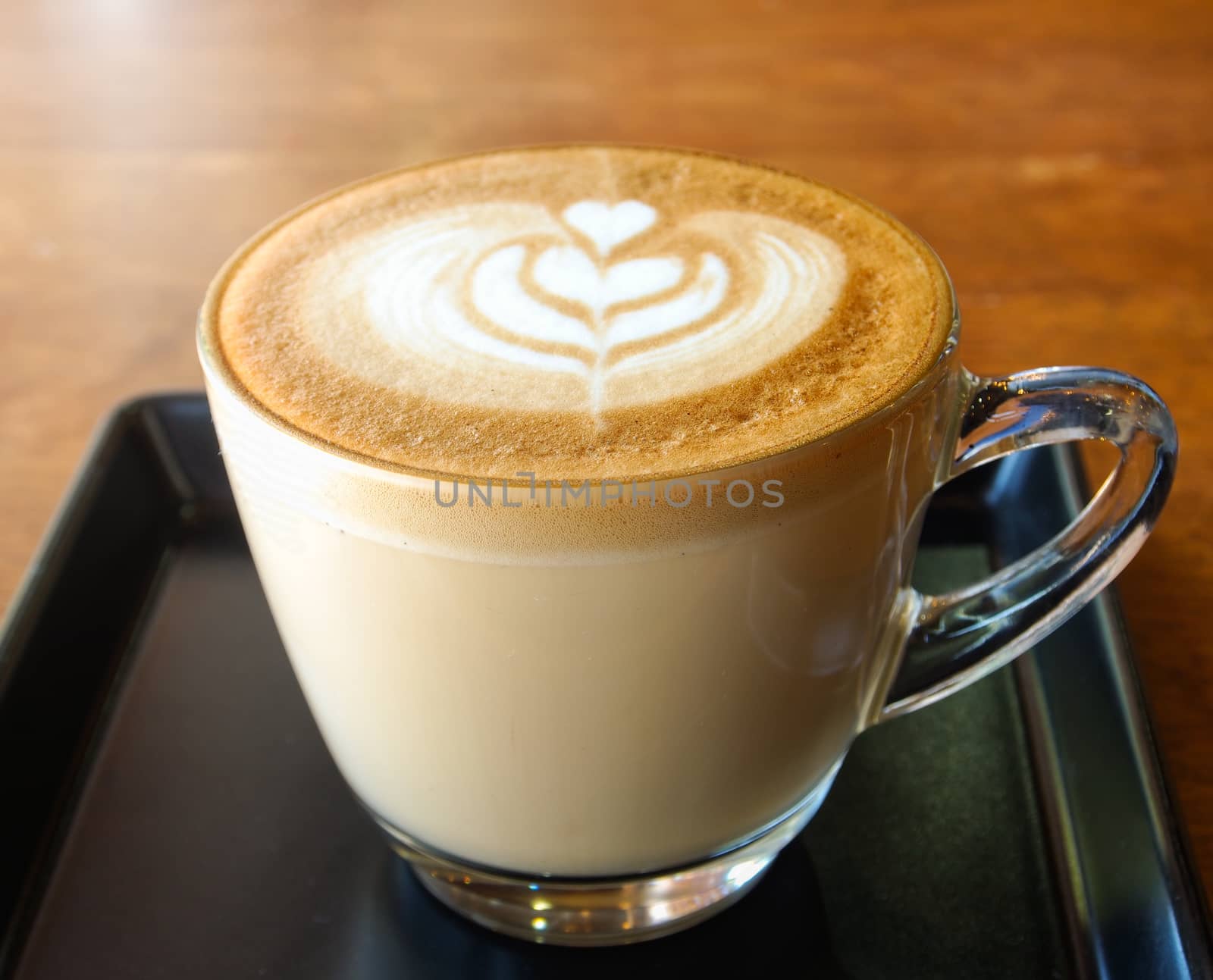 hot milk art coffee in cup in cafe . focus at glass edge