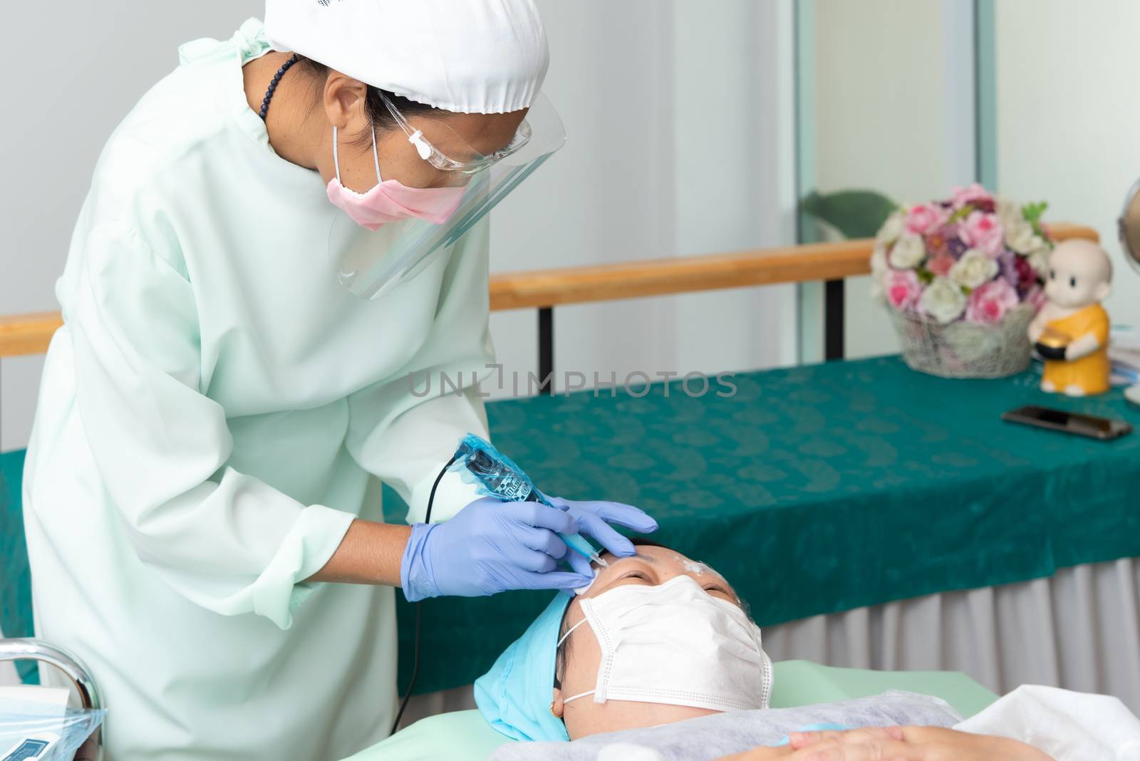 Bangkok, Thailand - May 30, 2020 : Unidentified Asian woman eyebrow tattooing by specialist in Eyebrow tattoo or embroidery clinic use COVID-19 prevention policy protect by use mask and face shield