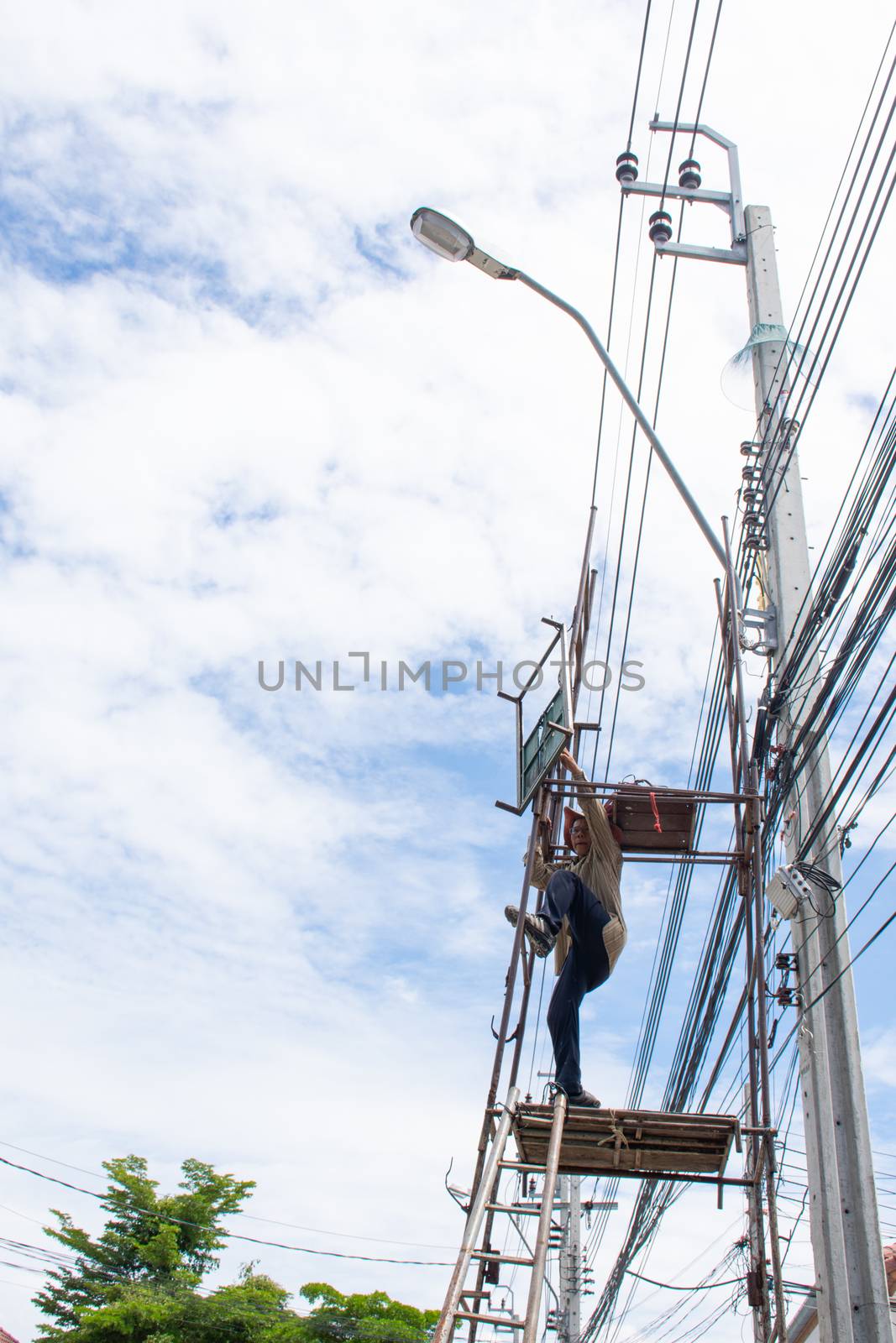 Bangkok, Thailand - June 26, 2016 : Unidentified electricians or handyman or worker risk working to install electric line on high pole by scaffolding on pickup truck at Bangkok Thailand.