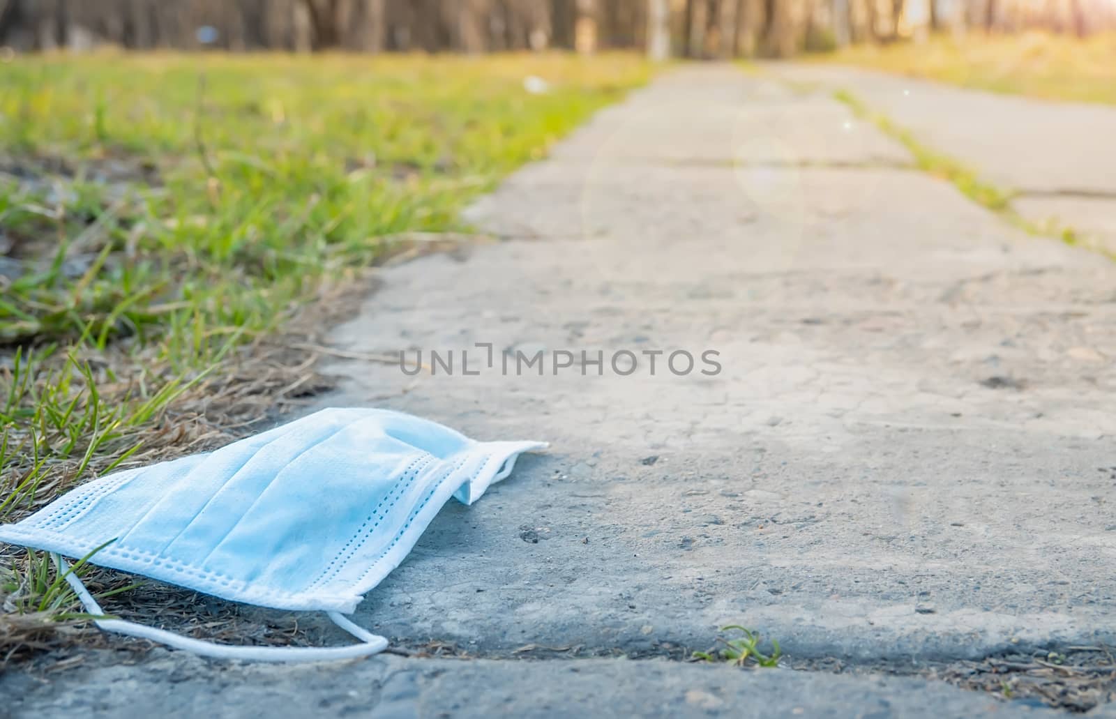 a medical mask lies on a footpath against the background of a city Park