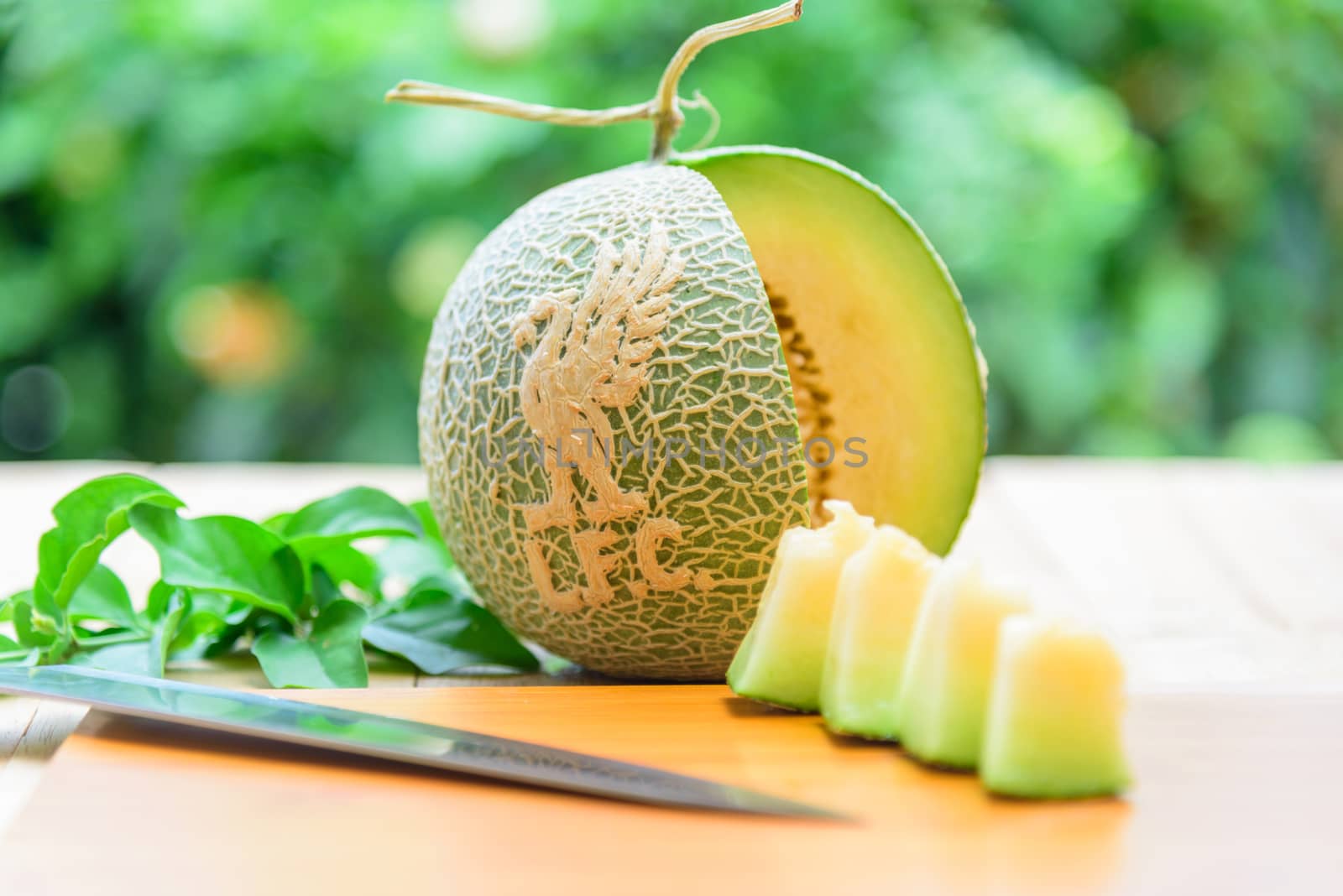 Fresh green melon with liverpool logo on wood plate