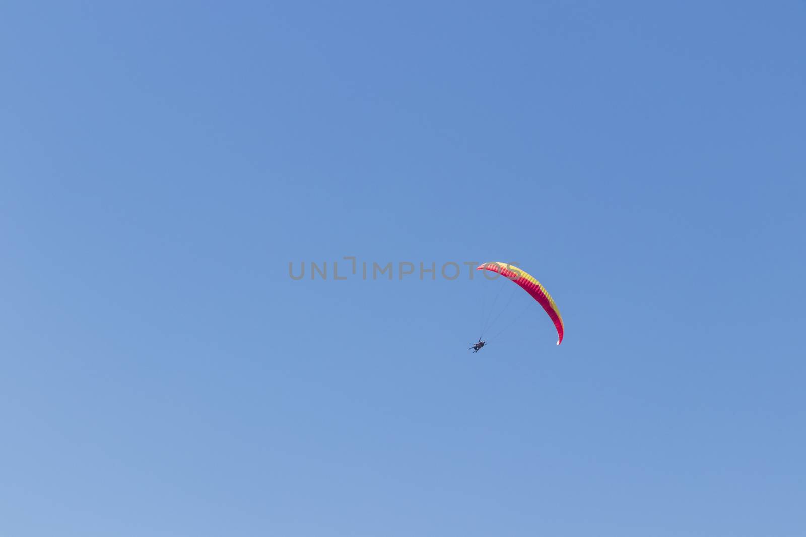 Colorful parachute aviator with blue sky. Paragliding by Arkadij