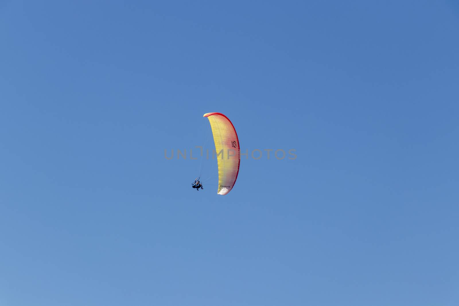 Colorful parachute aviator with blue sky. Paragliding by Arkadij