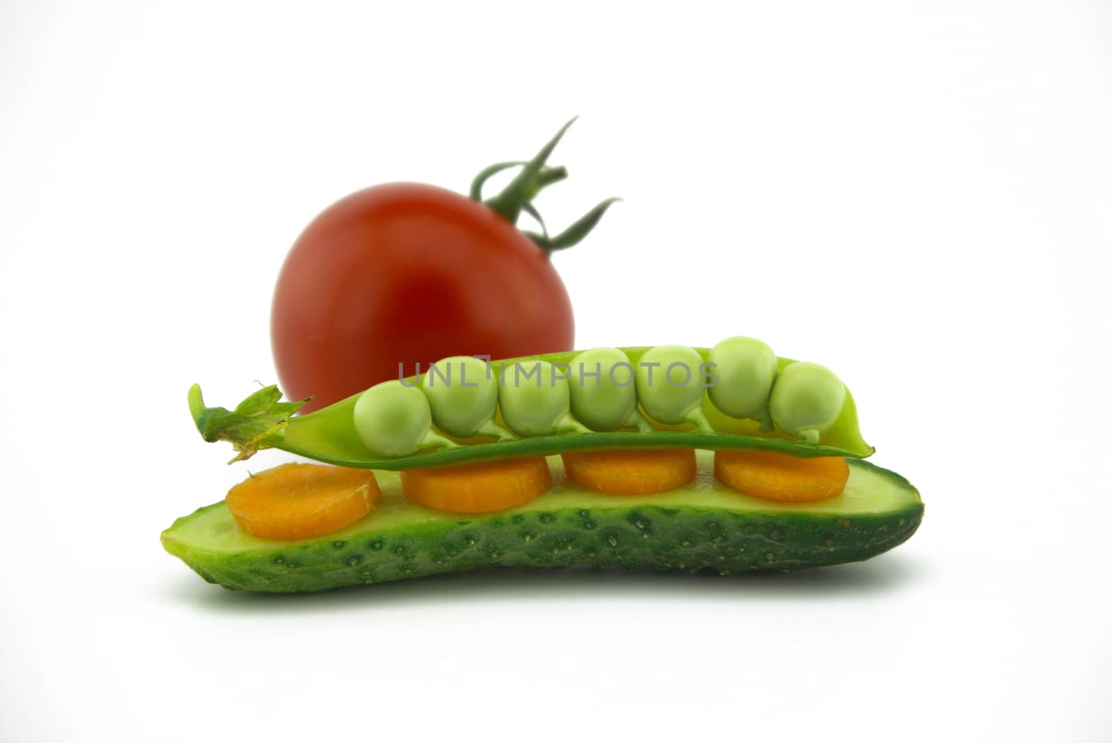 Healthy fresh vegetable sandwich over white with carrots, peas in a pod and cucumber balance on top of each other next to a red ripe tomato