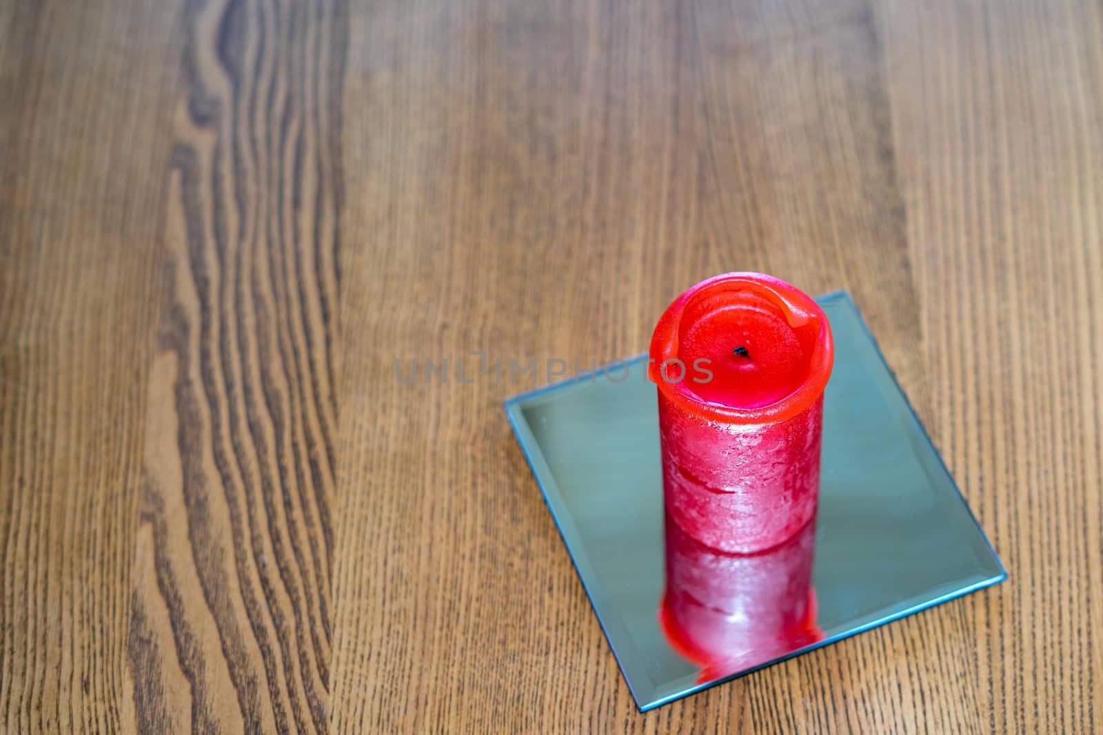 A thick red candle stands on the table. Side view. Place for text by Serhii_Voroshchuk