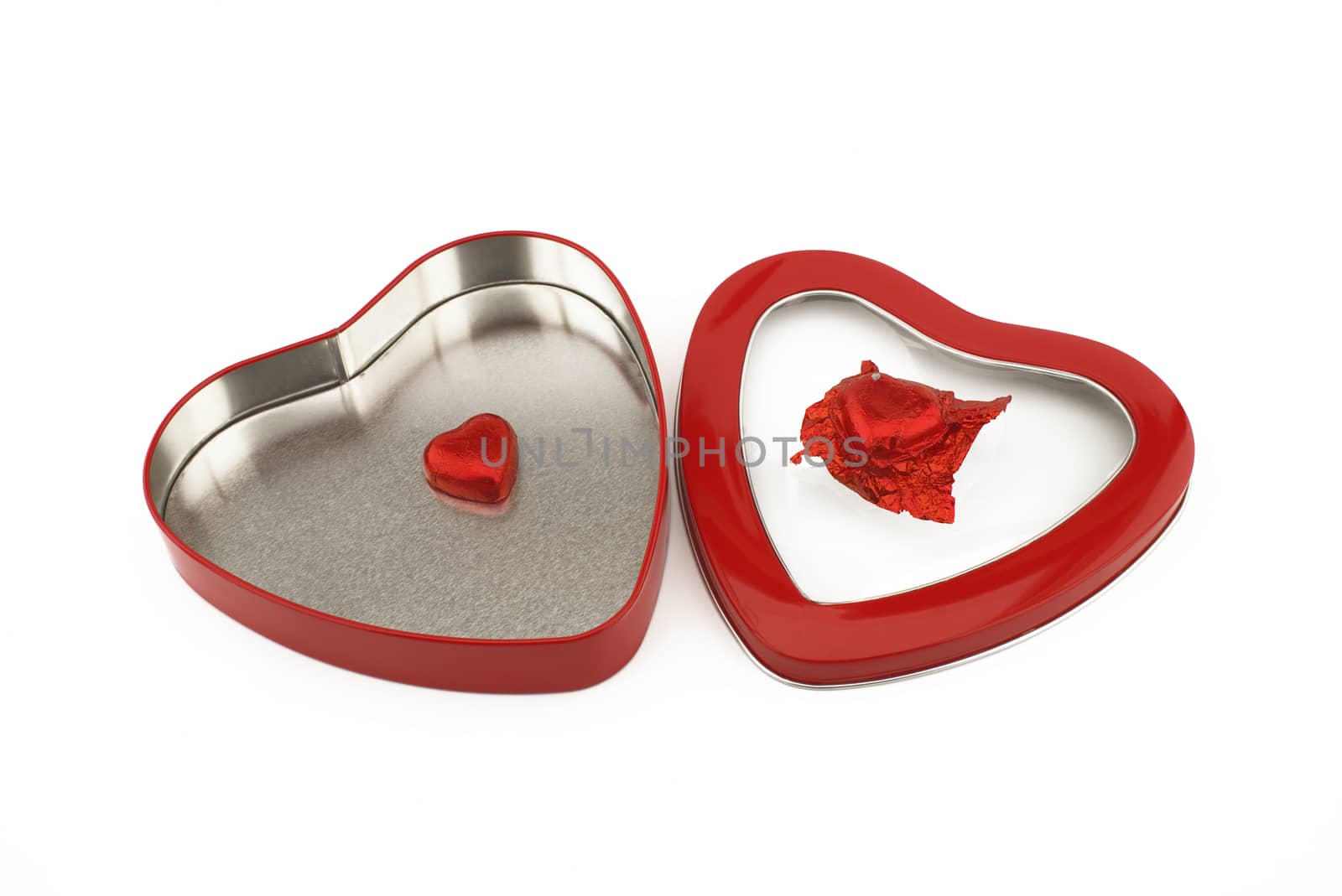 Red heart shaped box with chocolate candy on a white background with copyspace symbolic of love and romance for Valentines