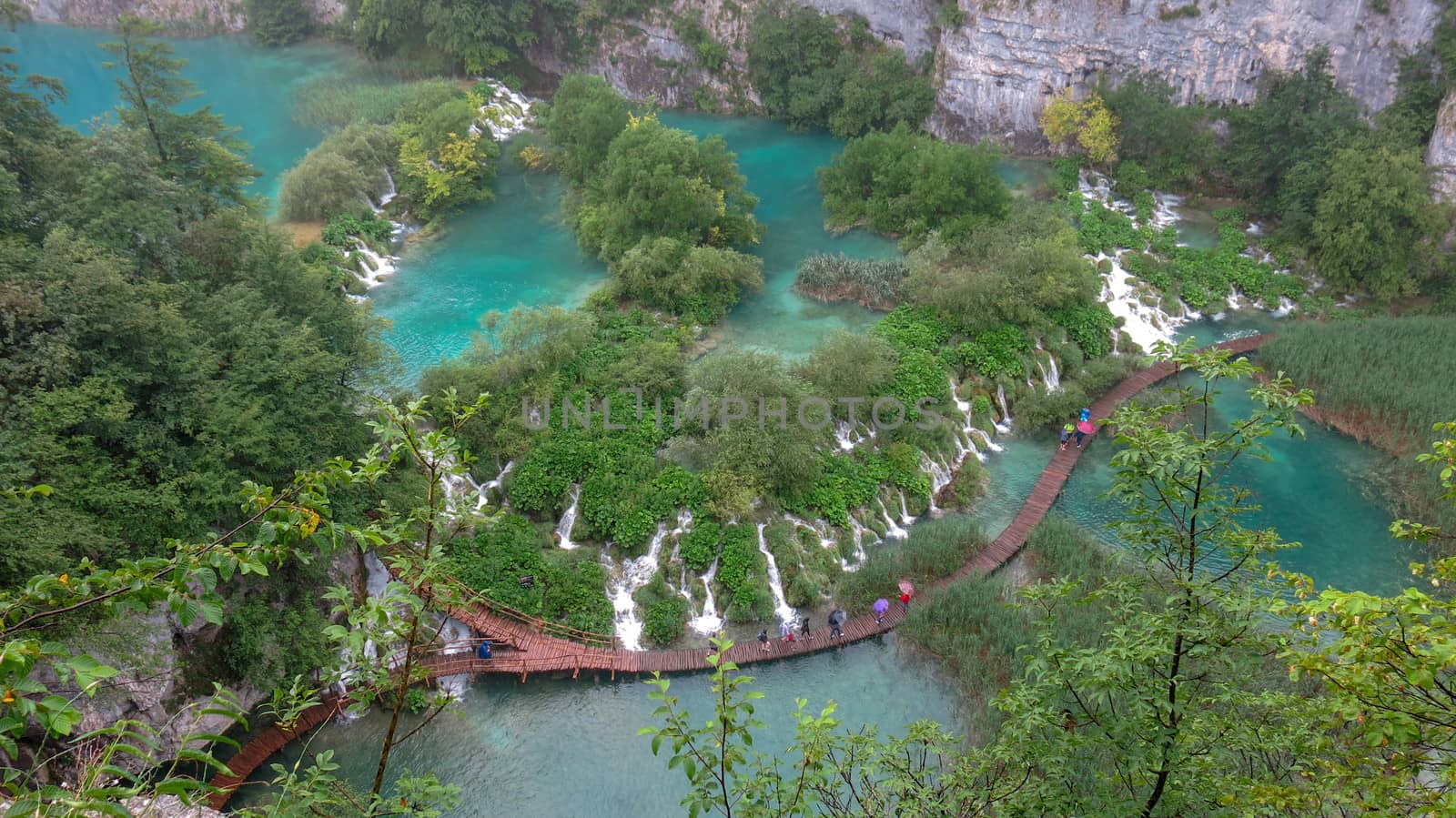 Tourists on the wooden park pathways enjoying the view of emerald lakes, cascades and crystal clear water, Plitvice Lakes National Park, Croatia by Sanatana2008
