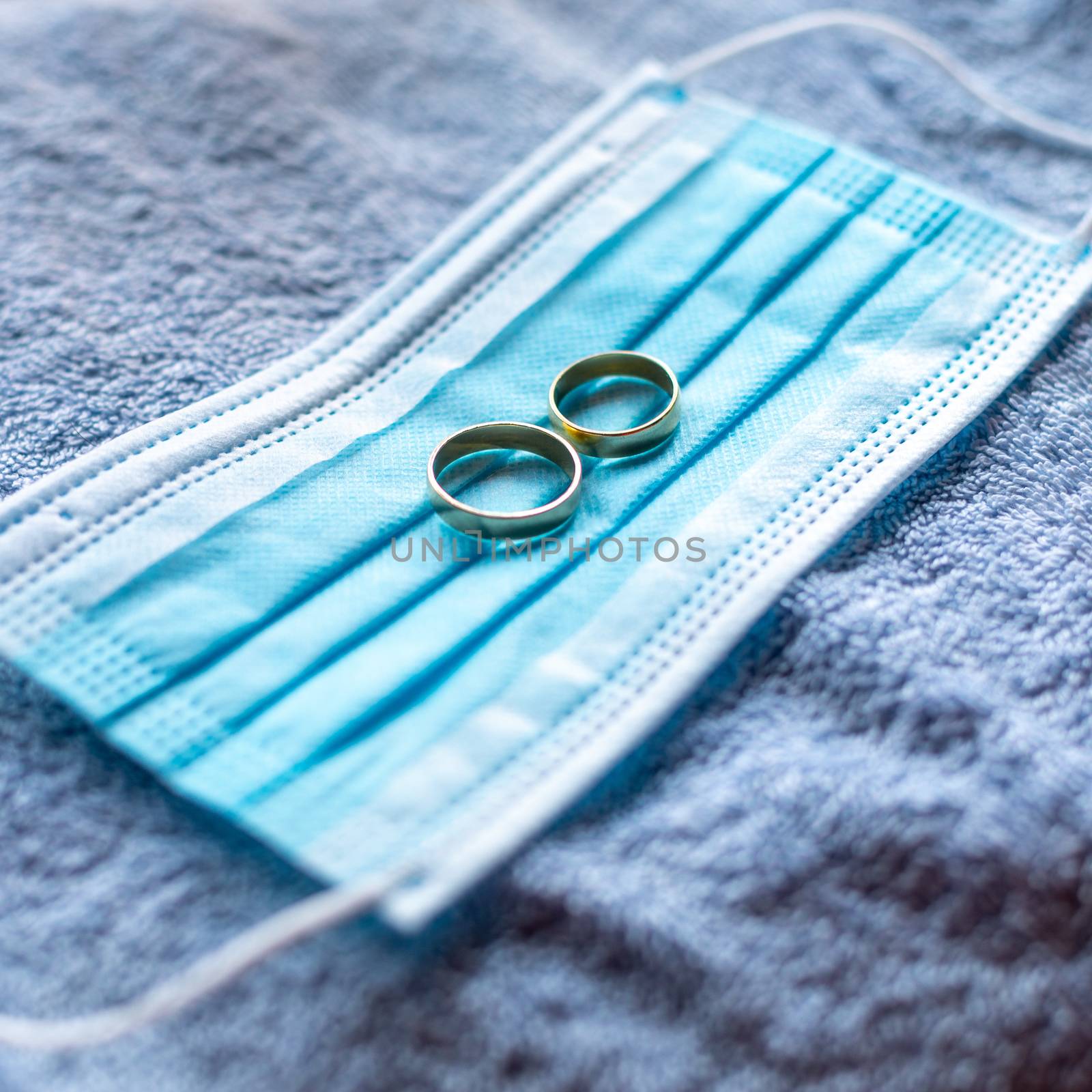 Wedding rings with surgical mask facemask - wedding and divorce metaphor in covid-19 pandemic time