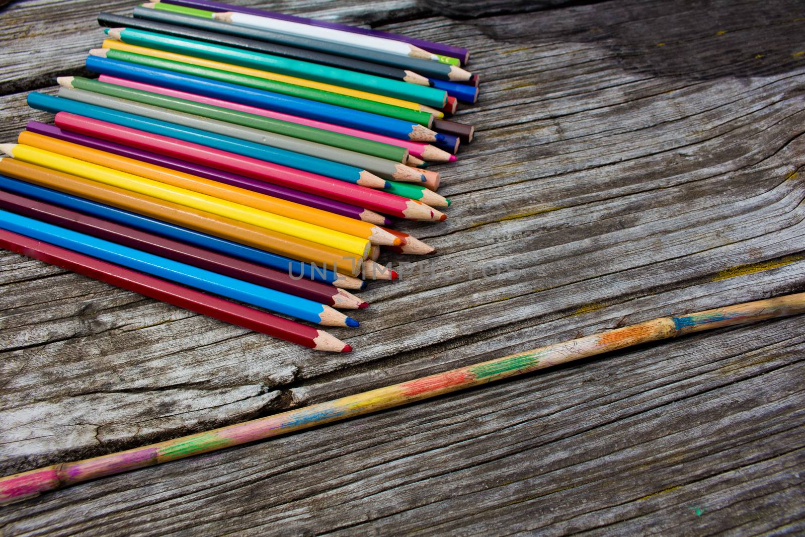 Colored pencils on wooden background and painted bamboostick. by Arkadij