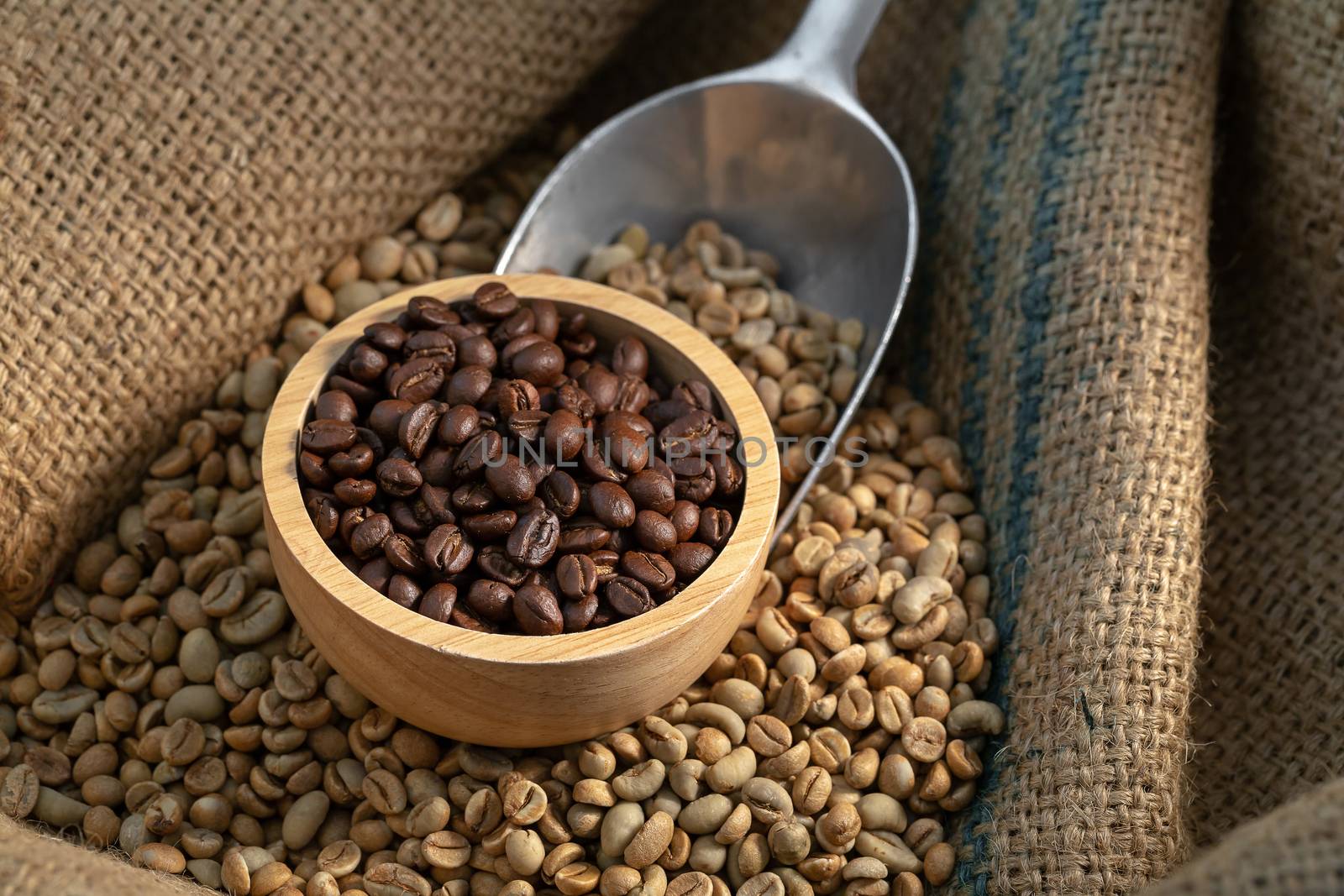 Coffee beans in canvas sack on wooden table in the dark light.