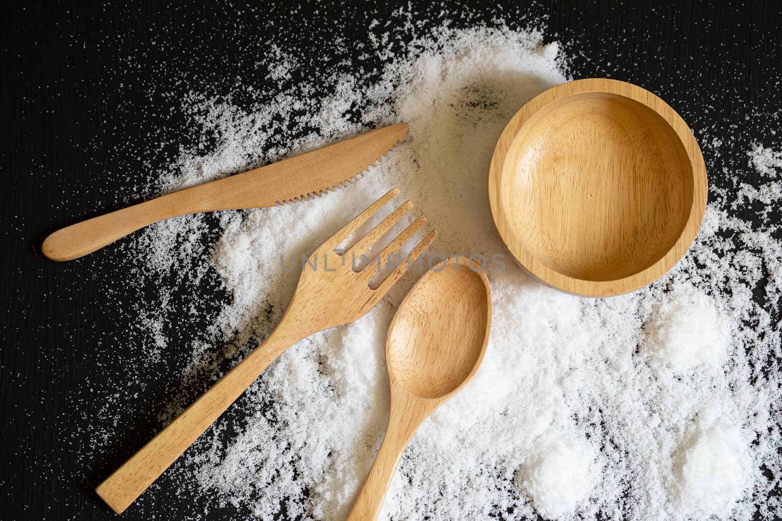 Spoons, forks and Dish made of wood on Salt powder and the back wooden background.