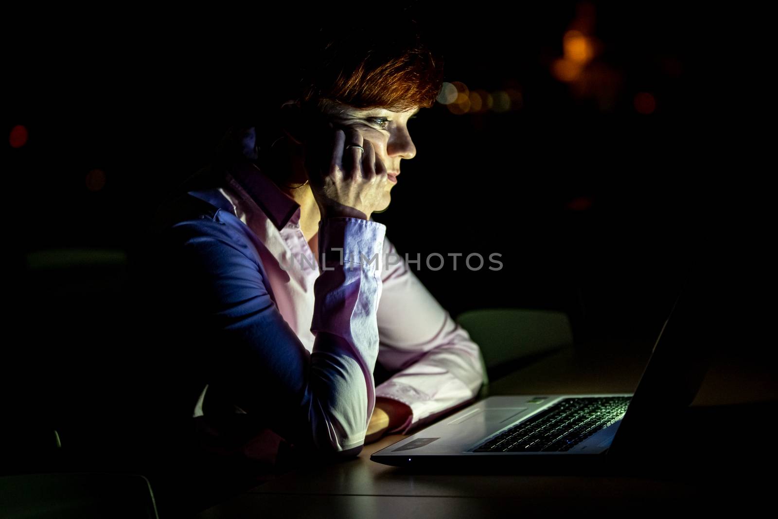Young beautiful woman on a university lecture working on a laptop at night by Edophoto