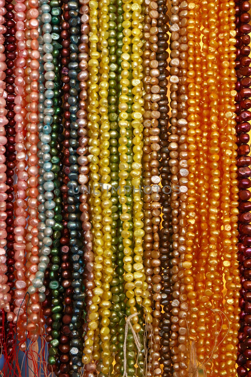 Close up many strings of colorful bead necklaces on retail display, low angle view