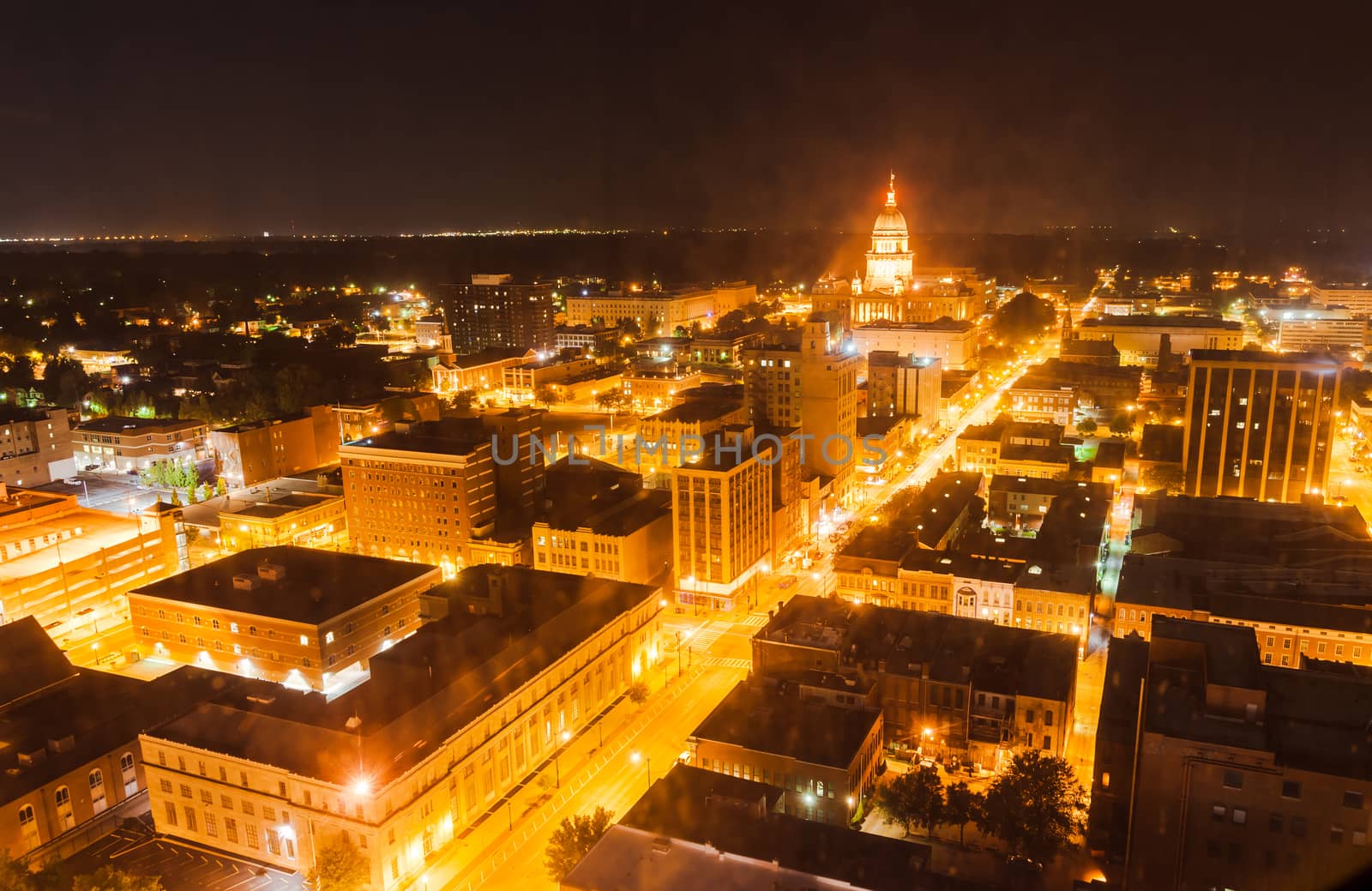 Springfield, Illinois, USA, night lights of city below with illuminated dome of state capiat building in haze of night.