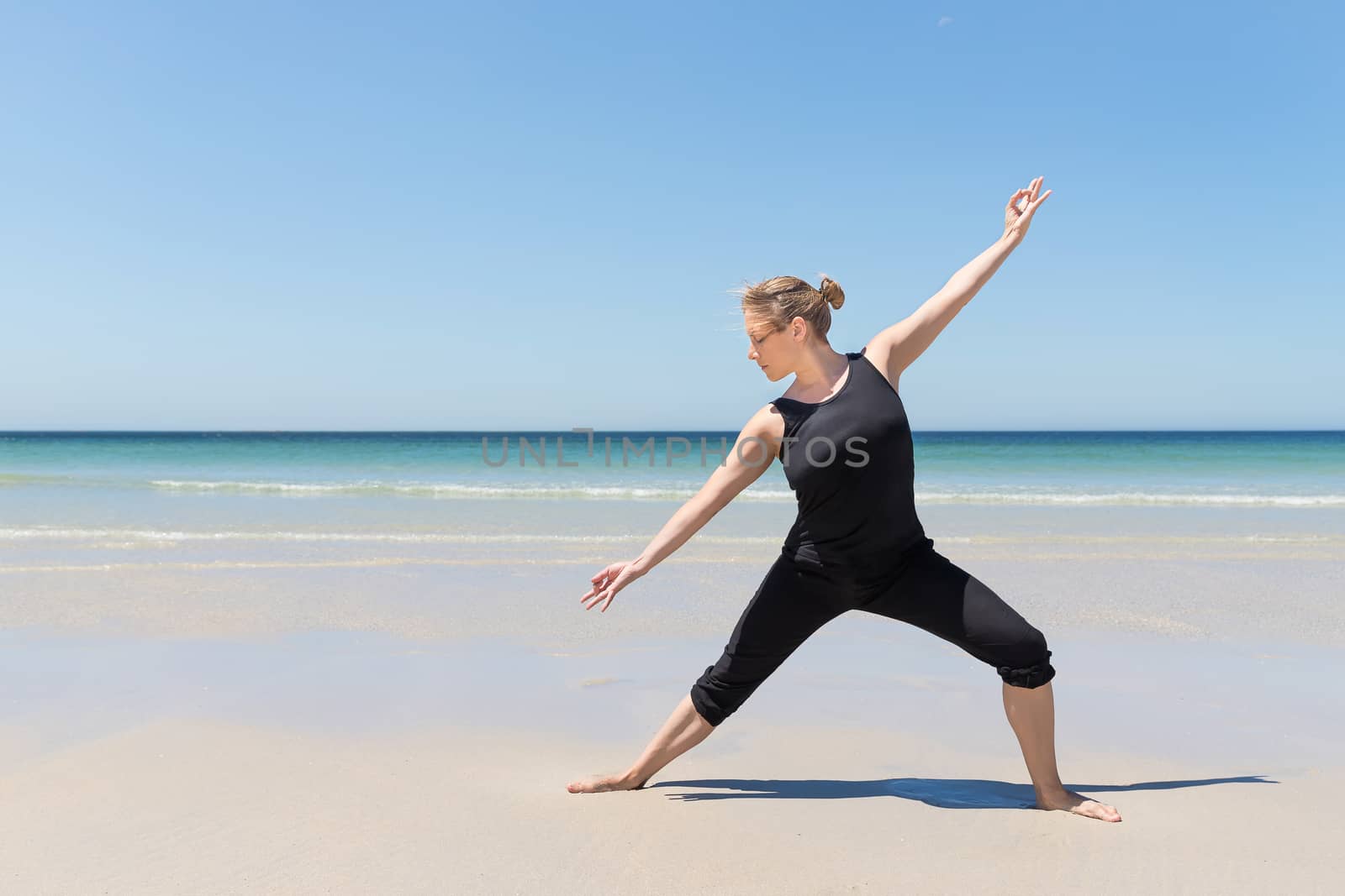 woman in meditation pose at the beach with the sea in the background