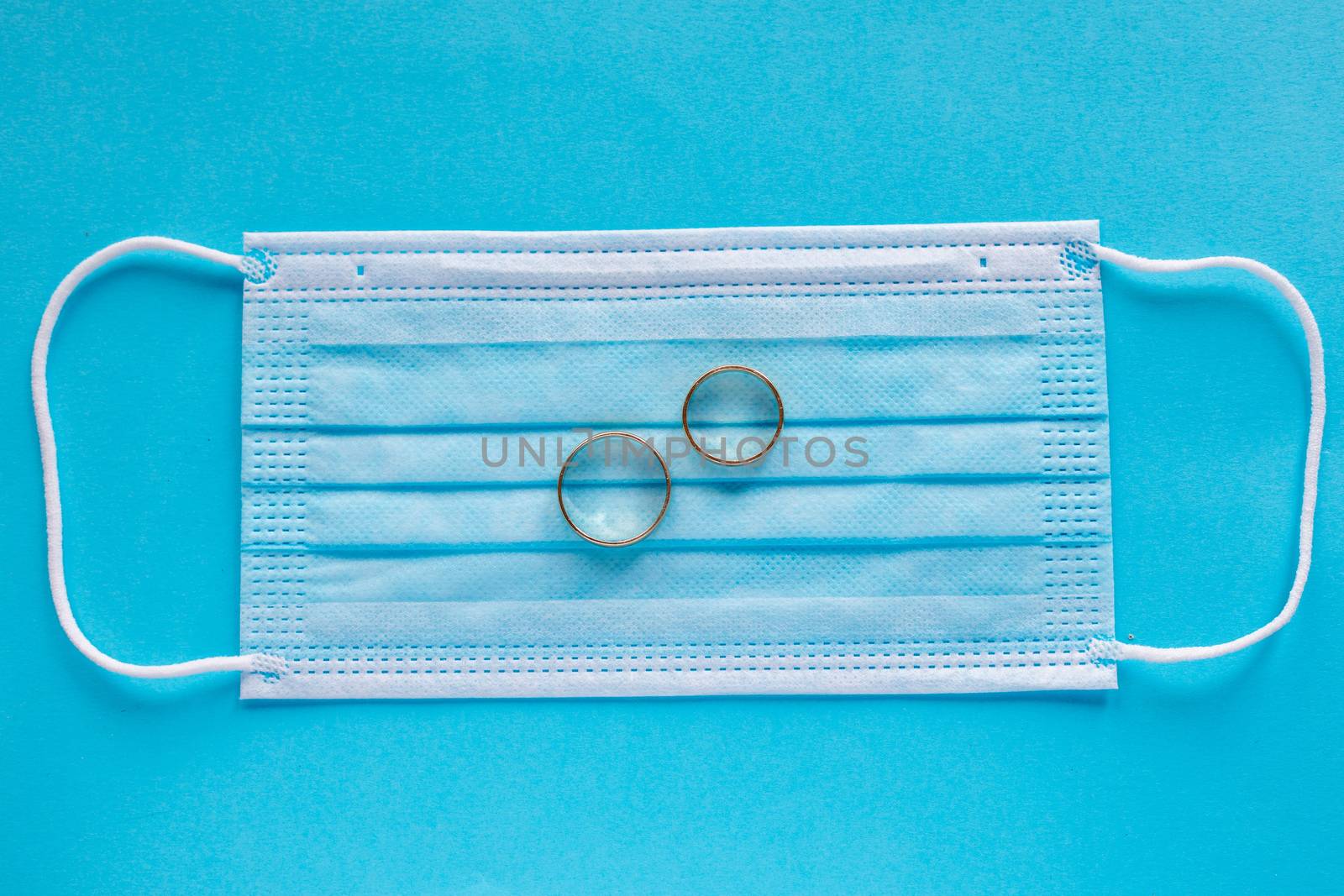 Wedding rings with surgical mask facemask - weddings and divorce concept in covid-19 pandemic time