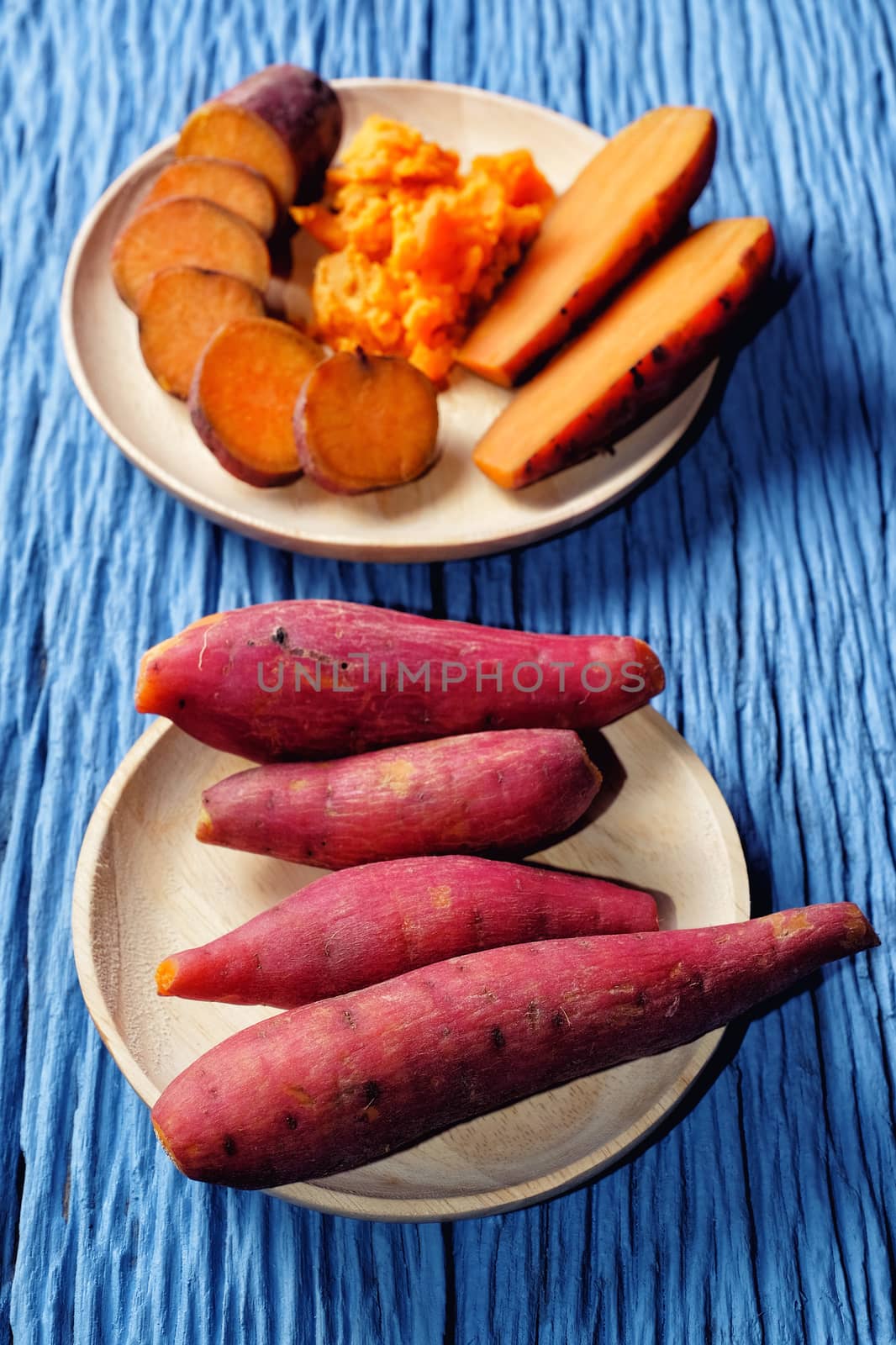 Sweet Potato on wooden cutting broad with blue wood background by Surasak
