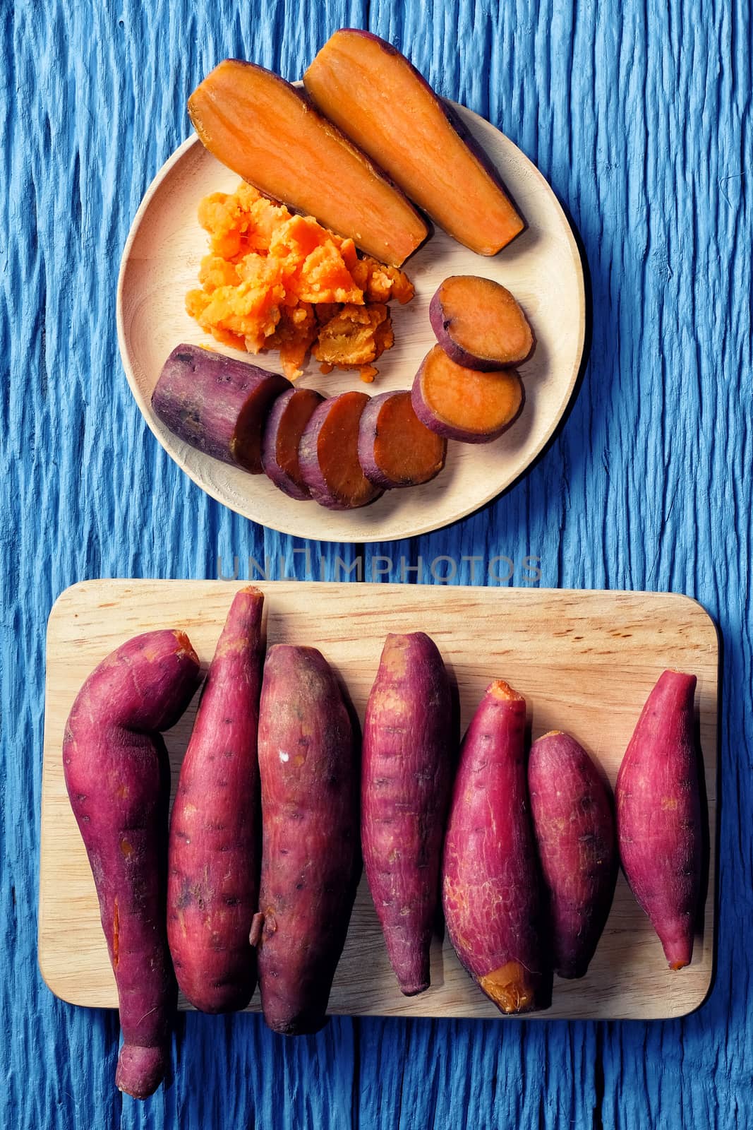 Sweet Potato on wooden cutting broad with blue wood background by Surasak