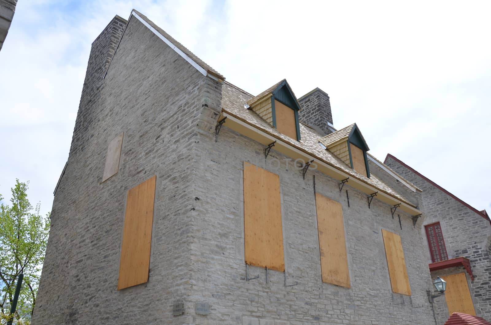 grey brick building with boarded up windows with wood boards