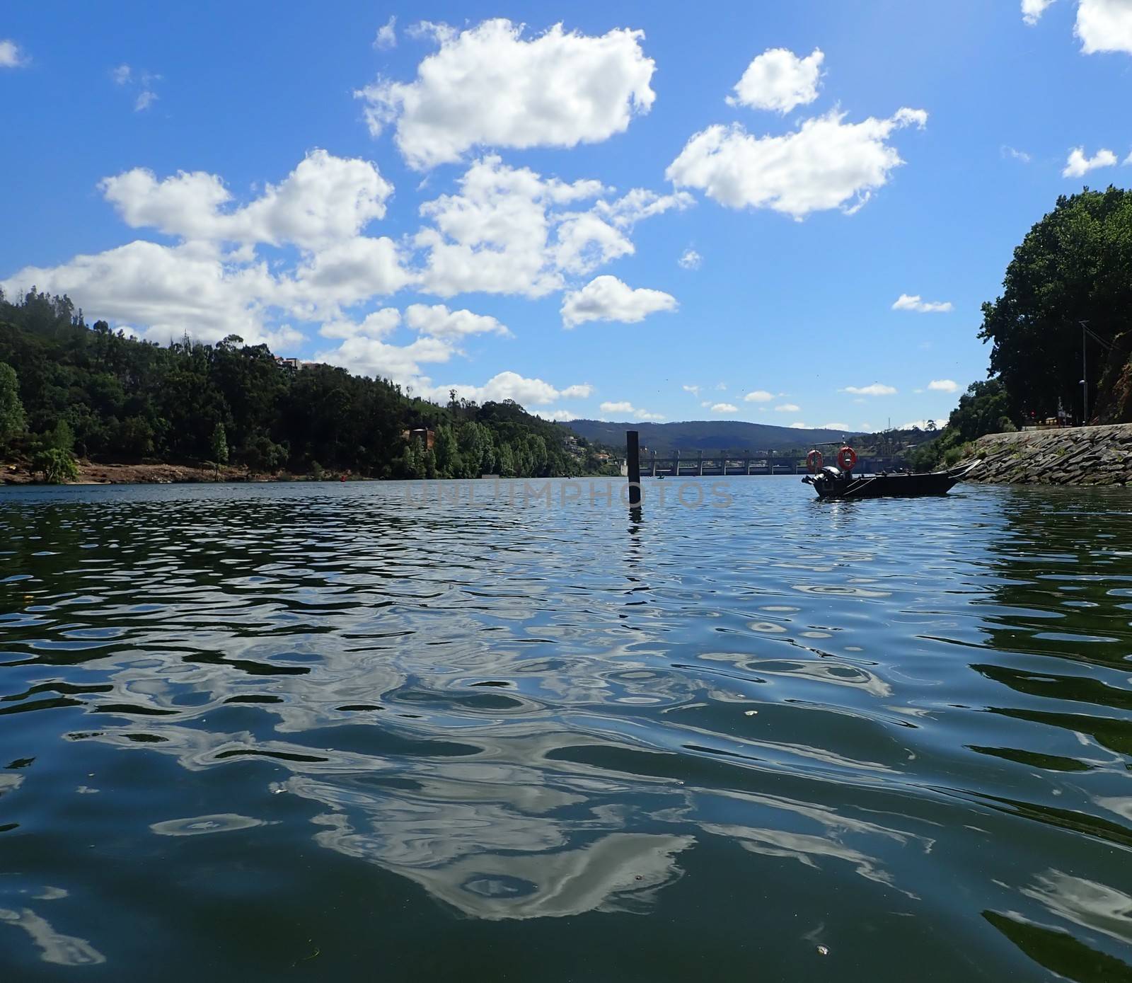 ripples on river water with boat and clouds by stockphotofan1