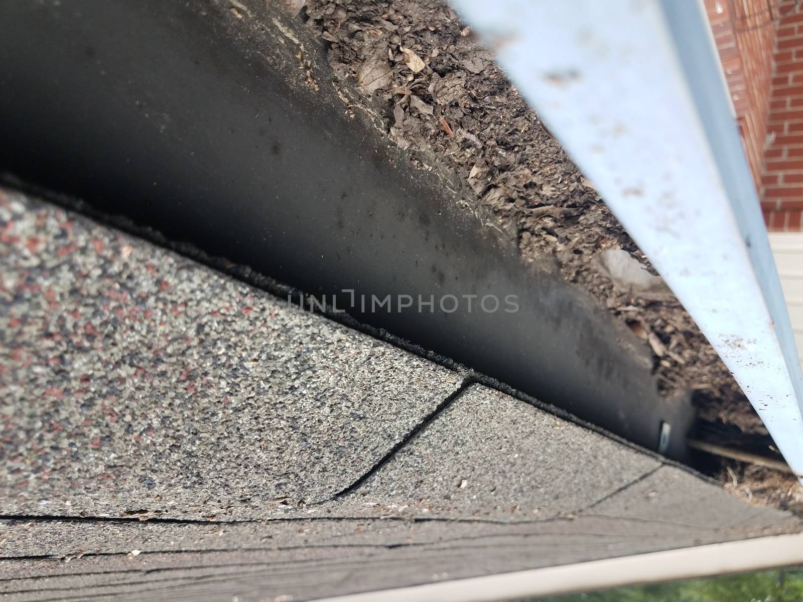 dirty metal gutter with roof shingles on house by stockphotofan1