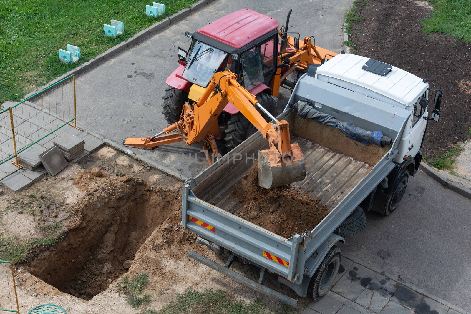 Belarus, Minsk-15.08.2018: Tractor with bucket excavator digs a hole and loads the earth into the body of a dump truck