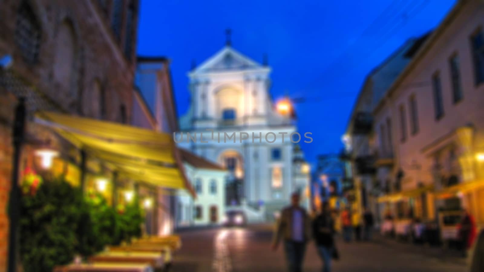 Blurred background. Evening city landscape, city street with lights and passers-by. Creative story for a background, poster, banner, or screensaver.
