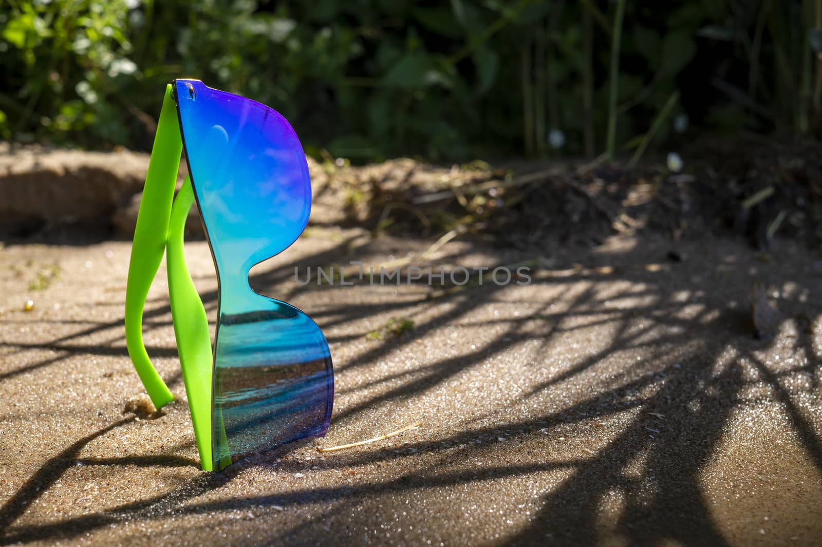 Pair of trendy modern sunglasses on coastal sand by NetPix