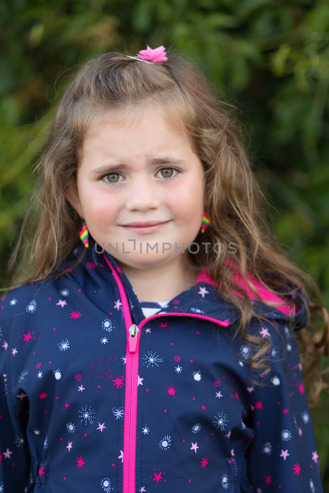 Closeup portrait of sad cute little girl with curly golden hair