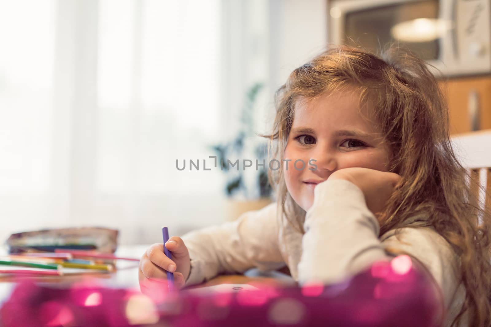 Smiling happy cute girl with long curly golden hair artist painting picture on paper. School homework concept