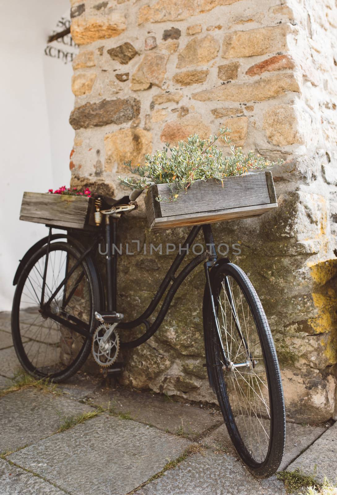 Retro style bicycle with flowers as a creative decoration near the shop in the cozy small street. Telc, Czech Republic