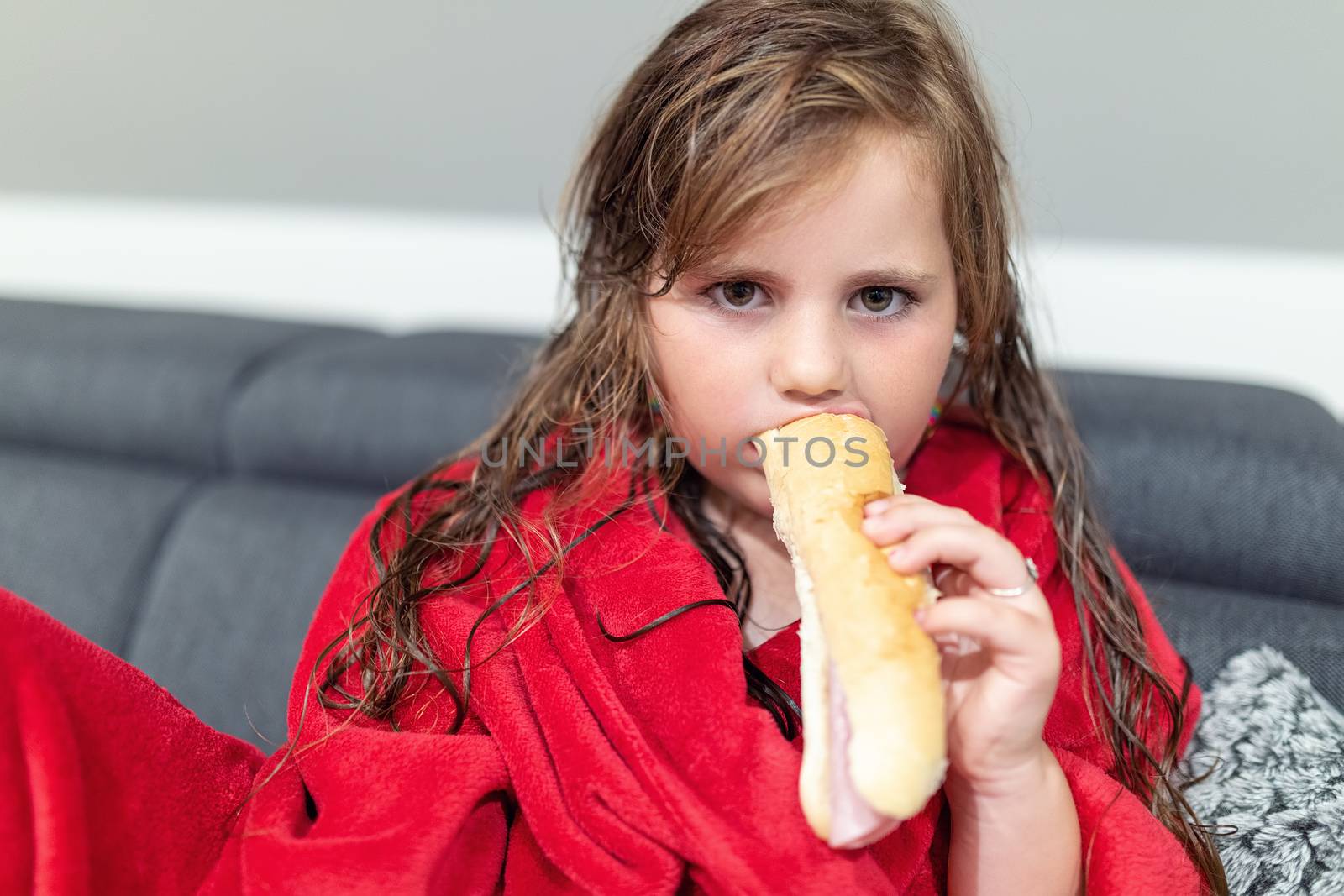 Closeup portrait of cute little girl with curly golden hair after bath dinner pastry with salami
