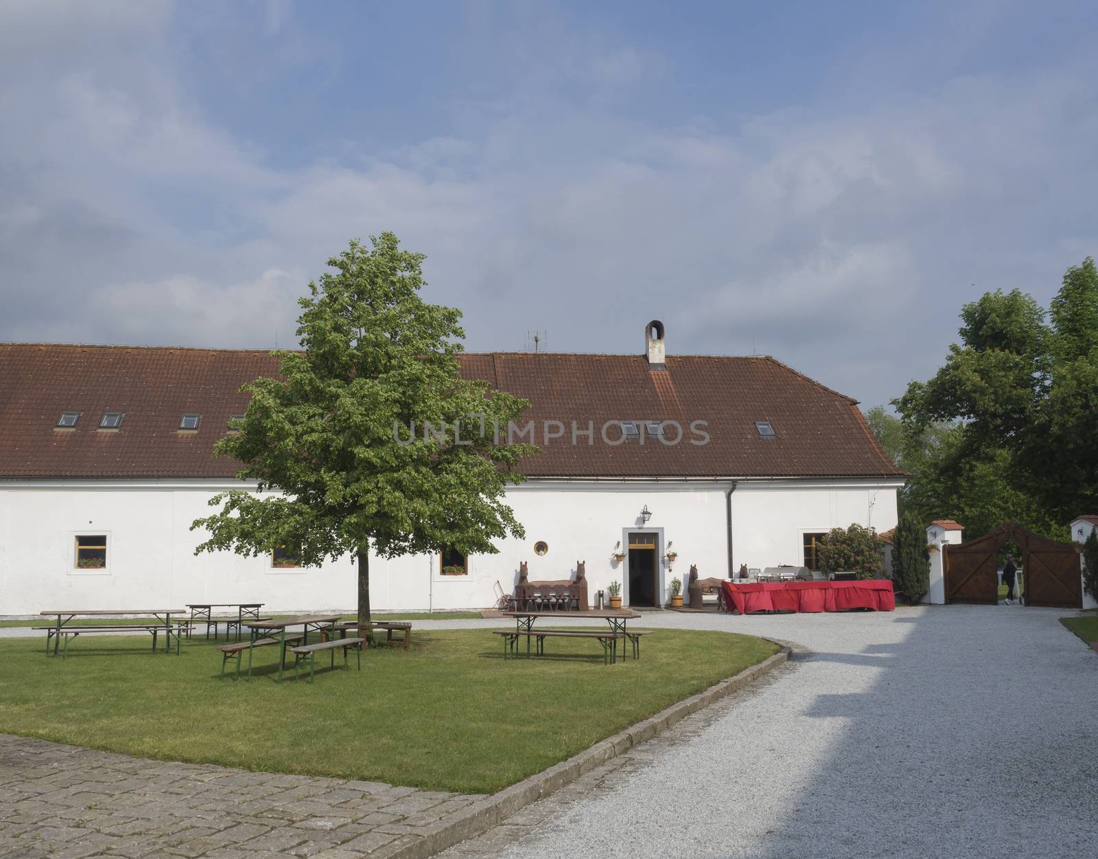 Czech republic, Benice; May 18, 2018: old baroque renovated homestead farm in Benice, building with empty court with buffet tables, green grass, tree and benches