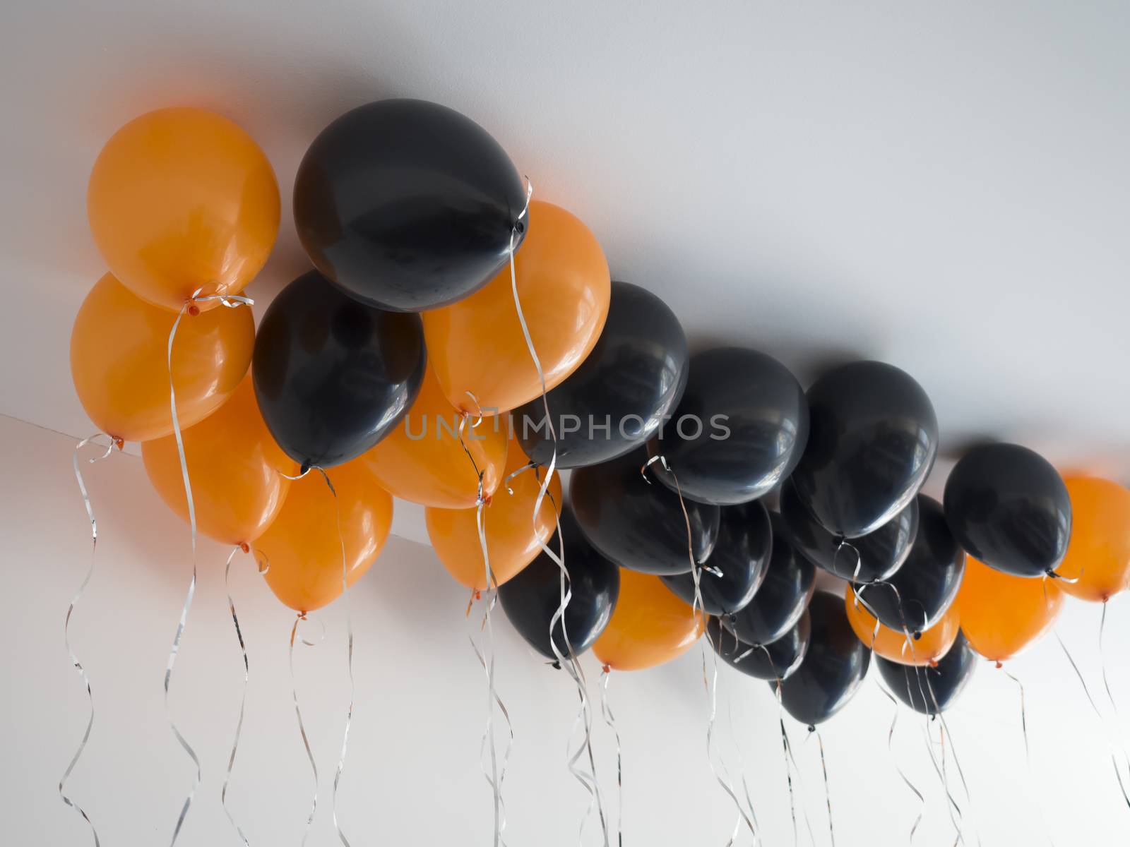 bunch of orange and black air balloons for halloween or birthday over white ceiling background. Holidays, decoration and party concept by Henkeova