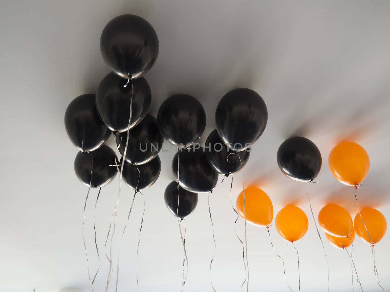 bunch of orange and black air balloons for halloween or birthday over white ceiling background. Holidays, decoration and party concept.