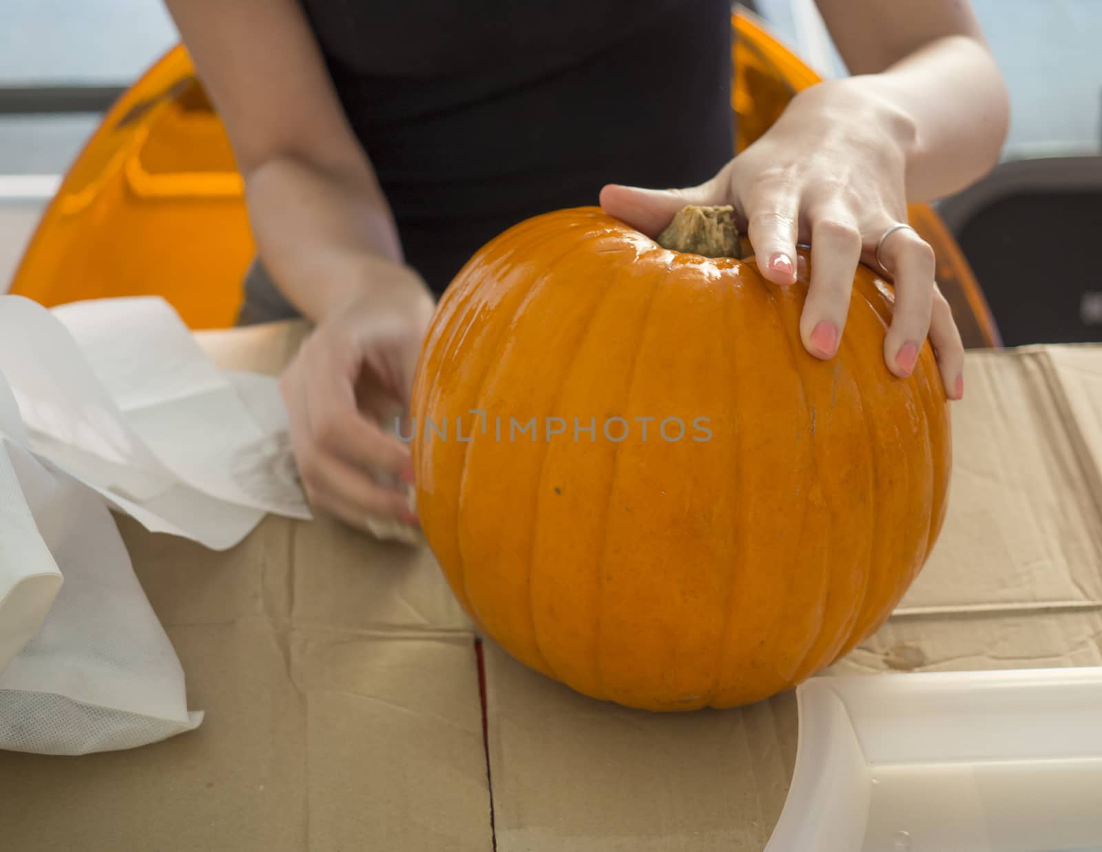 Process of carving pumpkin to make Jack-o-lantern. Creating traditional decoration for Halloween and Thanksgiving. Cutted orange pumpkin lay on table in woman hands