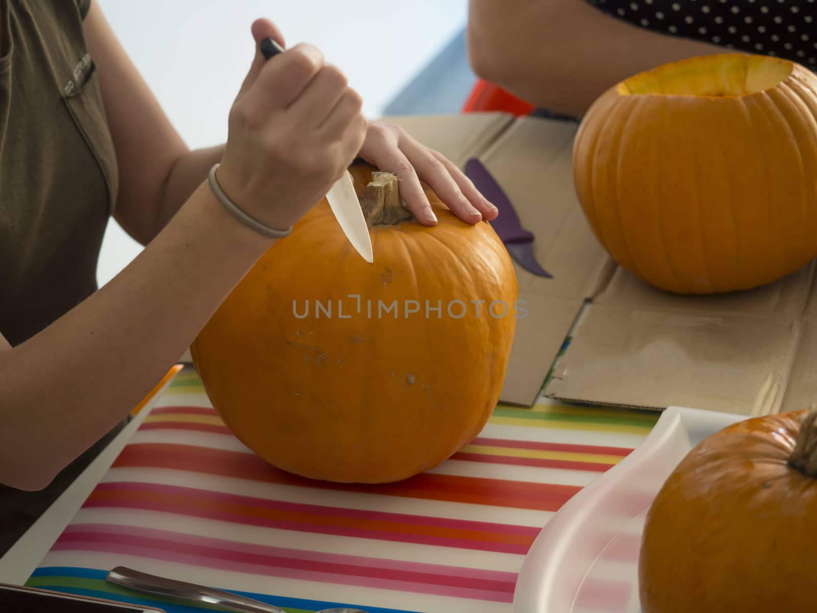 Process of carving pumpkin to make Jack-o-lantern. Creating traditional decoration for Halloween and Thanksgiving. Cutted orange pumpkin lay on table in woman hands