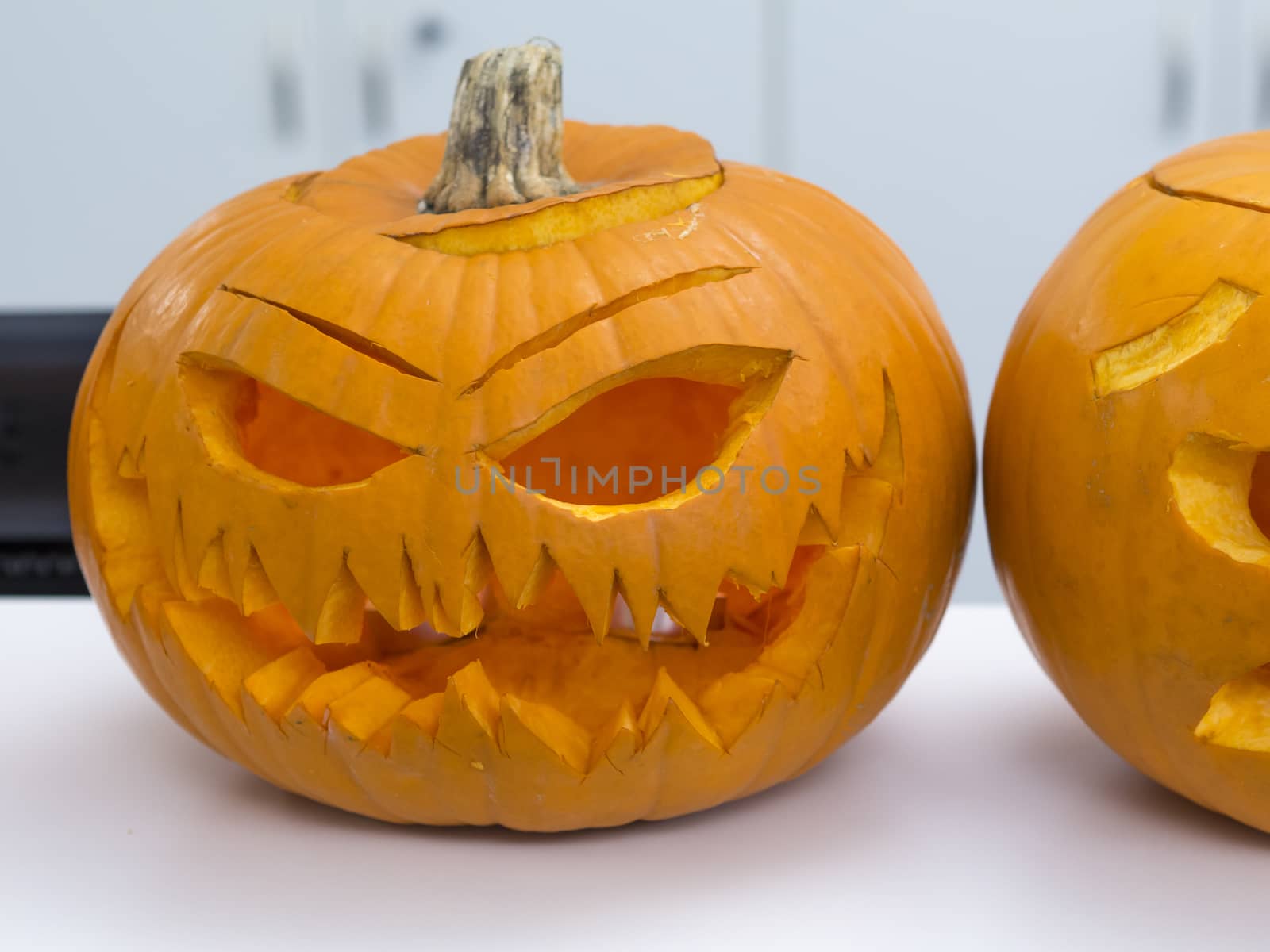 Halloween big orange pumpkin decorated with scary face. Jack O' Lantern on white table background by Henkeova