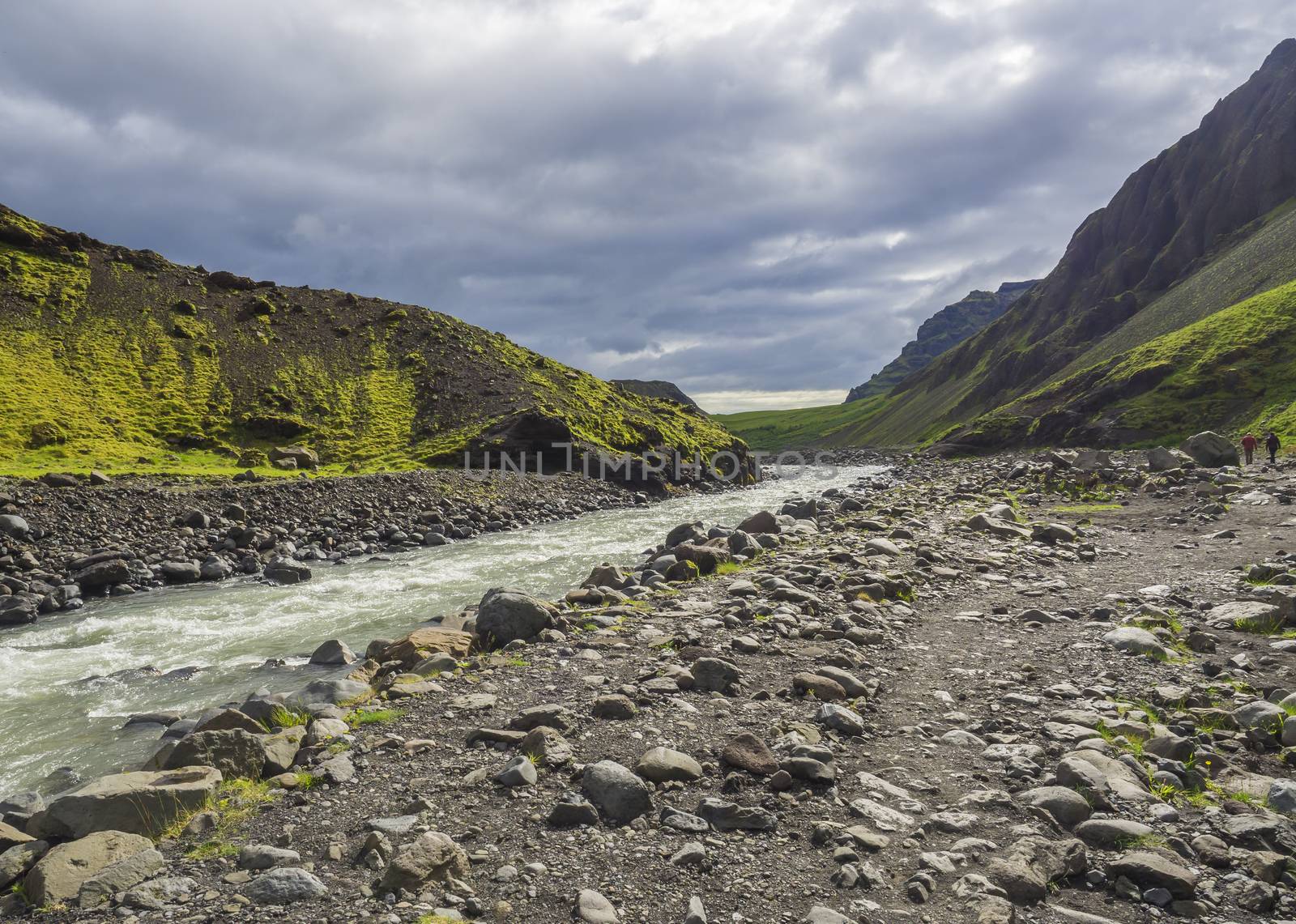 Footpath at Laugara river valley to Seljavallalaug abandoned theramal swimming pool in South Iceland, green hillos and dramatic sky.
